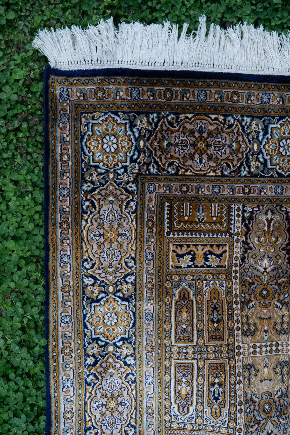 Carpet corner showing layered floral borders, rectangular ornamental panels and white fringe