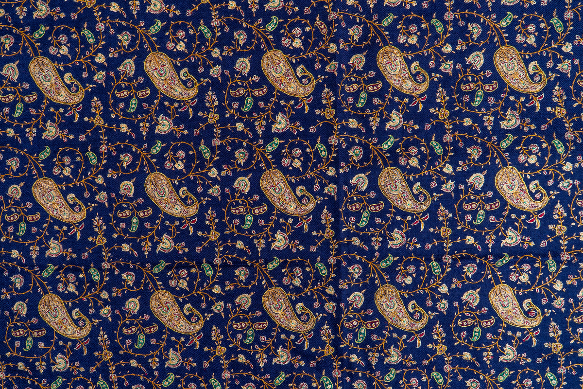 Close view of the blue shawl's embroidered field, with gold-toned paisleys among tiny green and crimson motifs