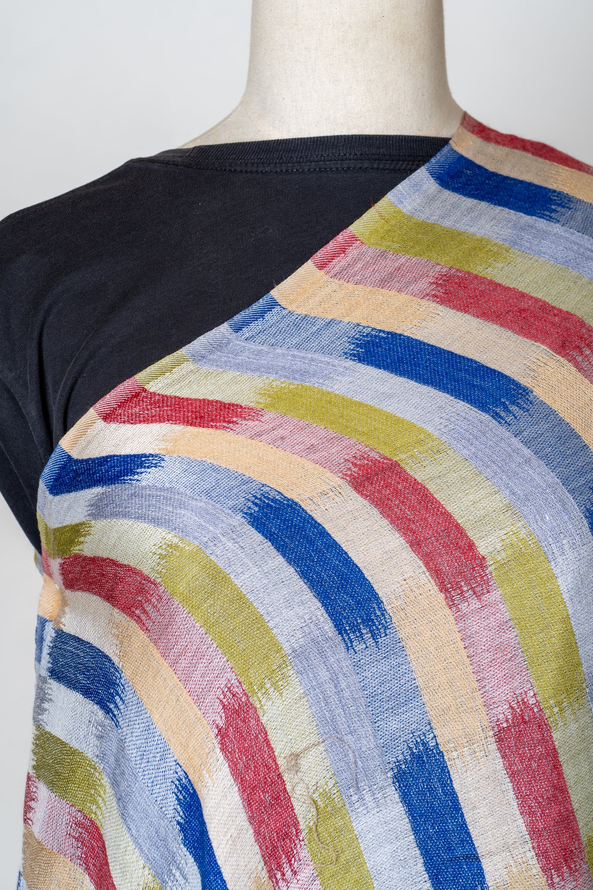Close view of the stole’s blue, rose, olive and pale ochre brushstroke print on a fine cream weave