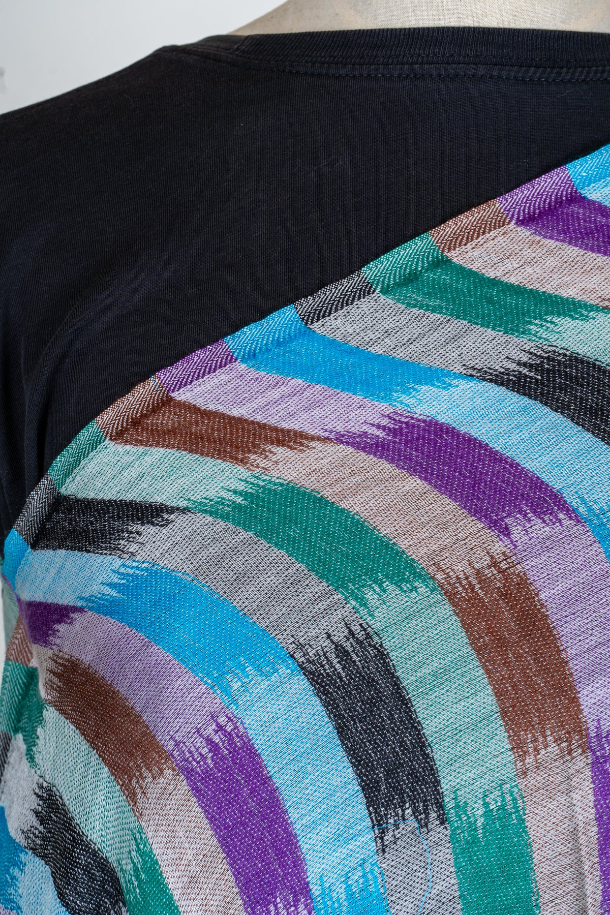 Shoulder close-up of the stole with brush-like blue, teal, purple and brown blocks and a fine visible weave.
