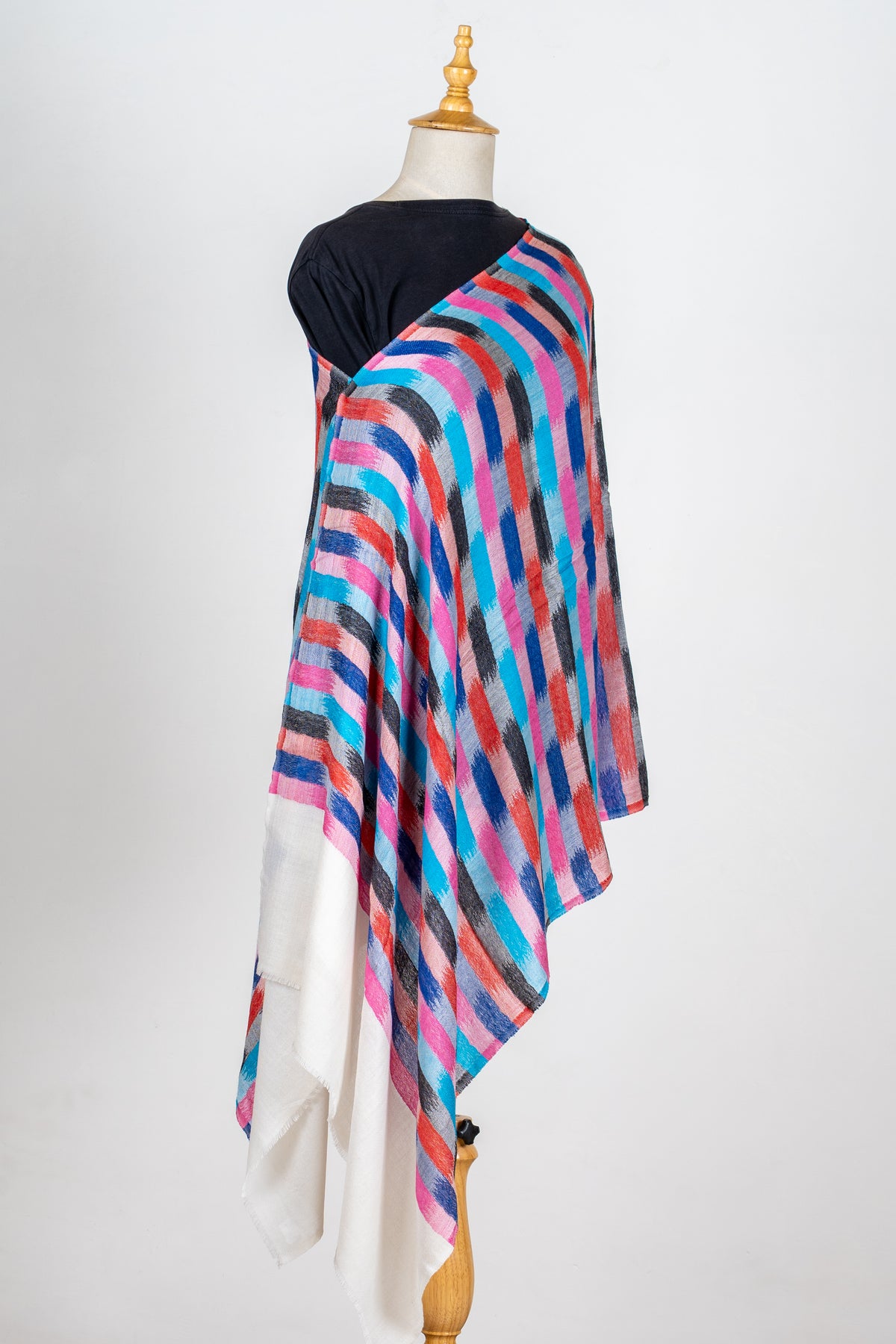 Full view of the brightly printed stole draped over one shoulder of a mannequin, with plain ivory ends hanging below