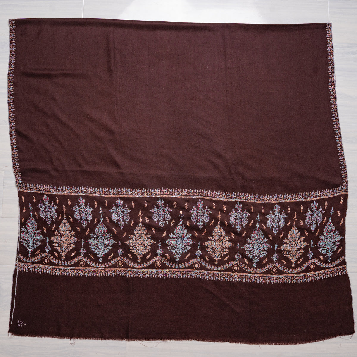 Chocolate-brown Pashmina shawl laid flat, with a plain centre above a band of pastel embroidered floral bouquets and small sprigs.
