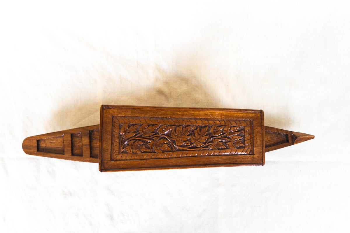Top view of a walnut wood shikara model showing its leaf-carved canopy and narrow pointed hull