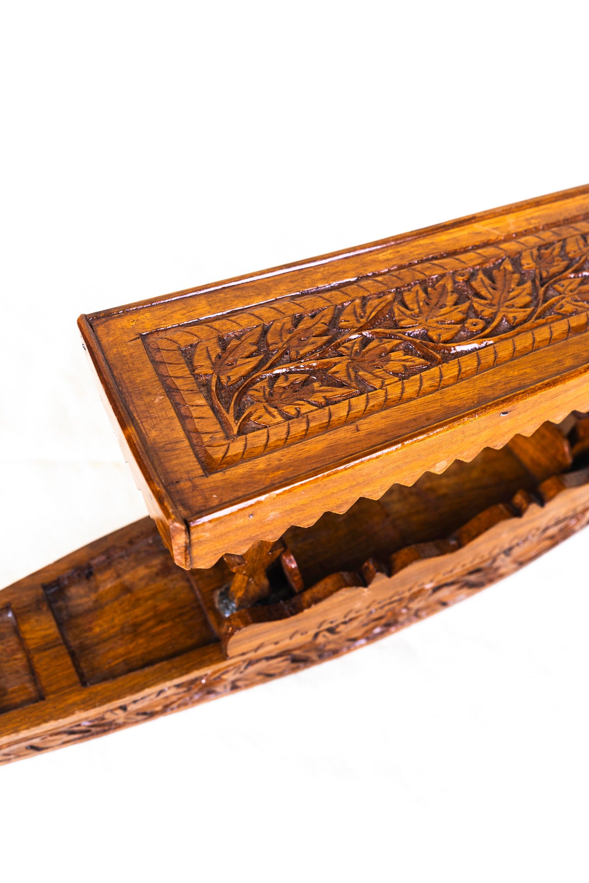 Angled close-up of a walnut wood shikara's carved canopy, scalloped trim, supporting posts and open seating area