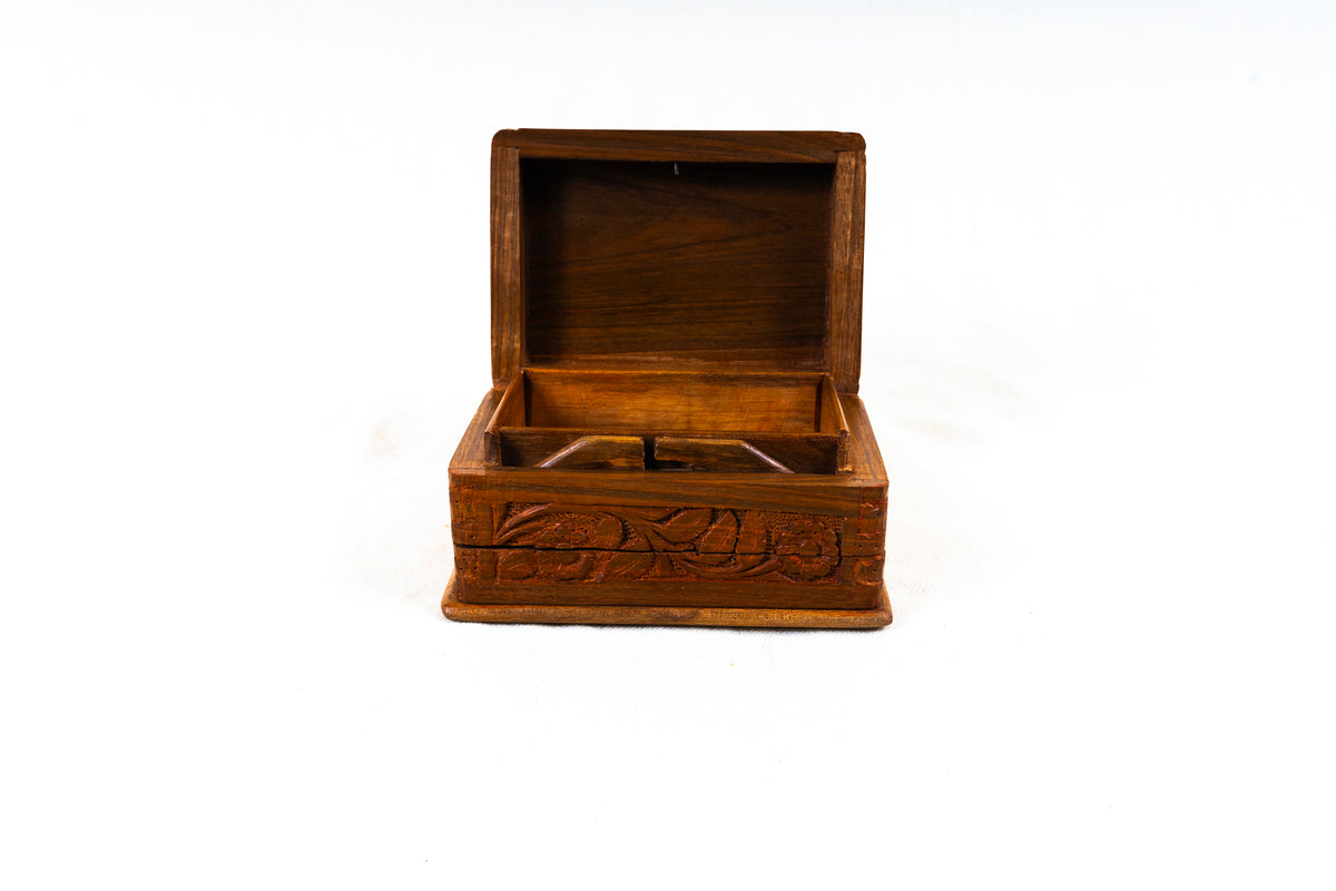 Front view of an open walnut wood box showing its hinged lid, wooden interior and carved floral front
