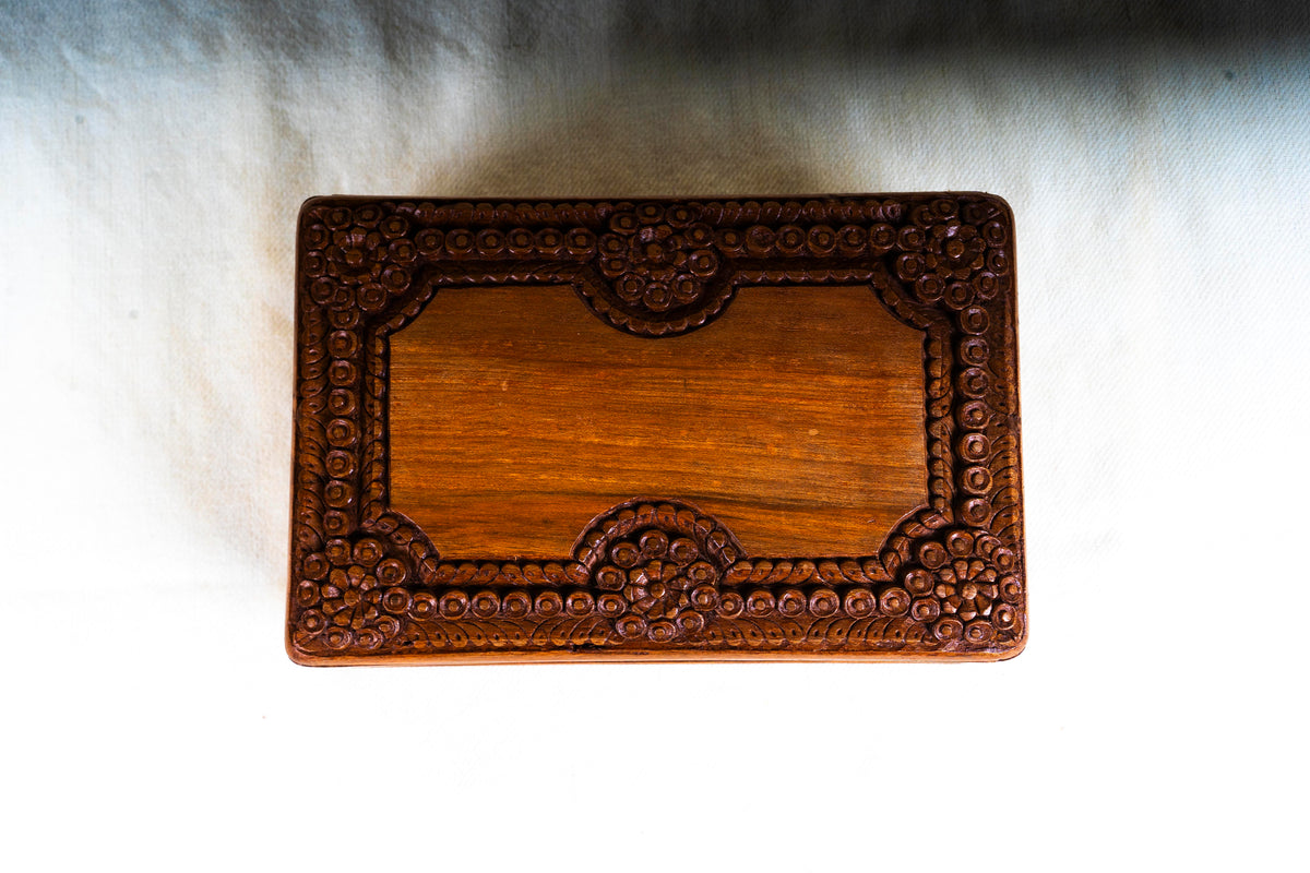 Overhead view of the closed walnut box, showing rosette clusters around the smooth golden-brown lid centre.