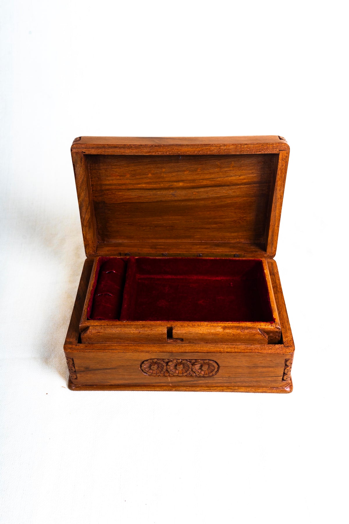Open walnut box viewed from the front, showing red velvet-lined compartments beneath a plain wooden lid interior.