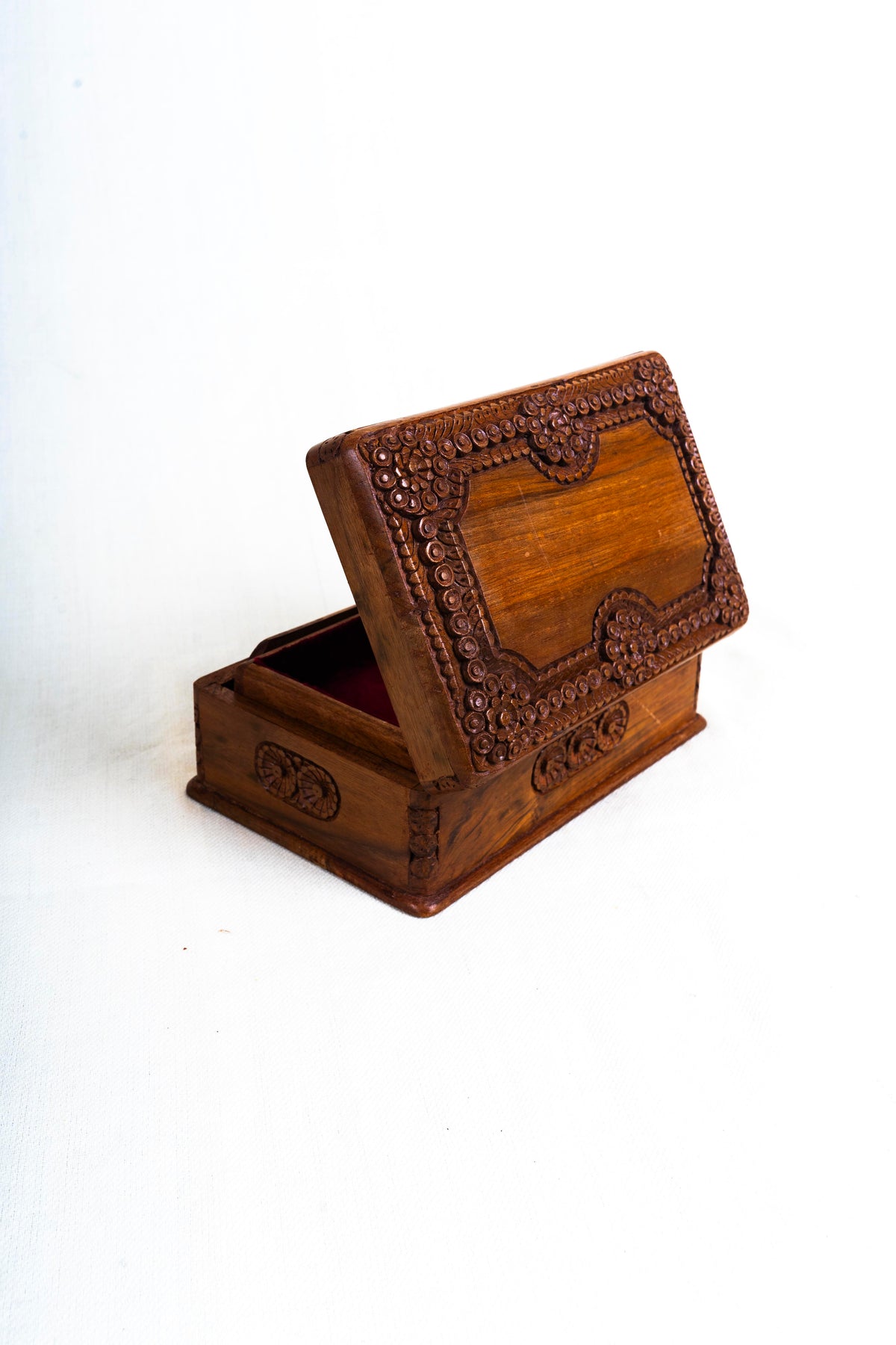 Rear view of the partly open walnut box, displaying the carved floral frame on the outside of the raised lid.