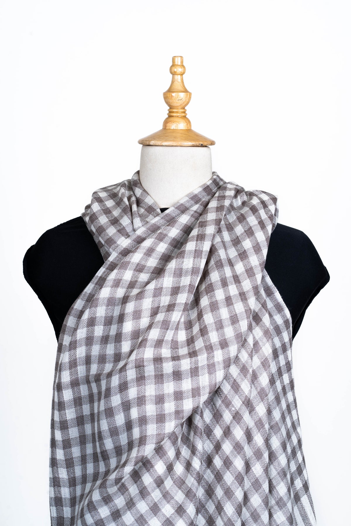 Taupe and white checked stole wrapped across a mannequin’s chest in a broad layered drape.