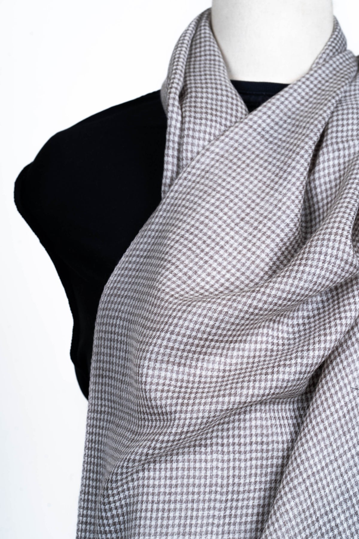 Close-up of the mini-check stole loosely draped across a mannequin chest, showing its fine grey and ivory pattern.