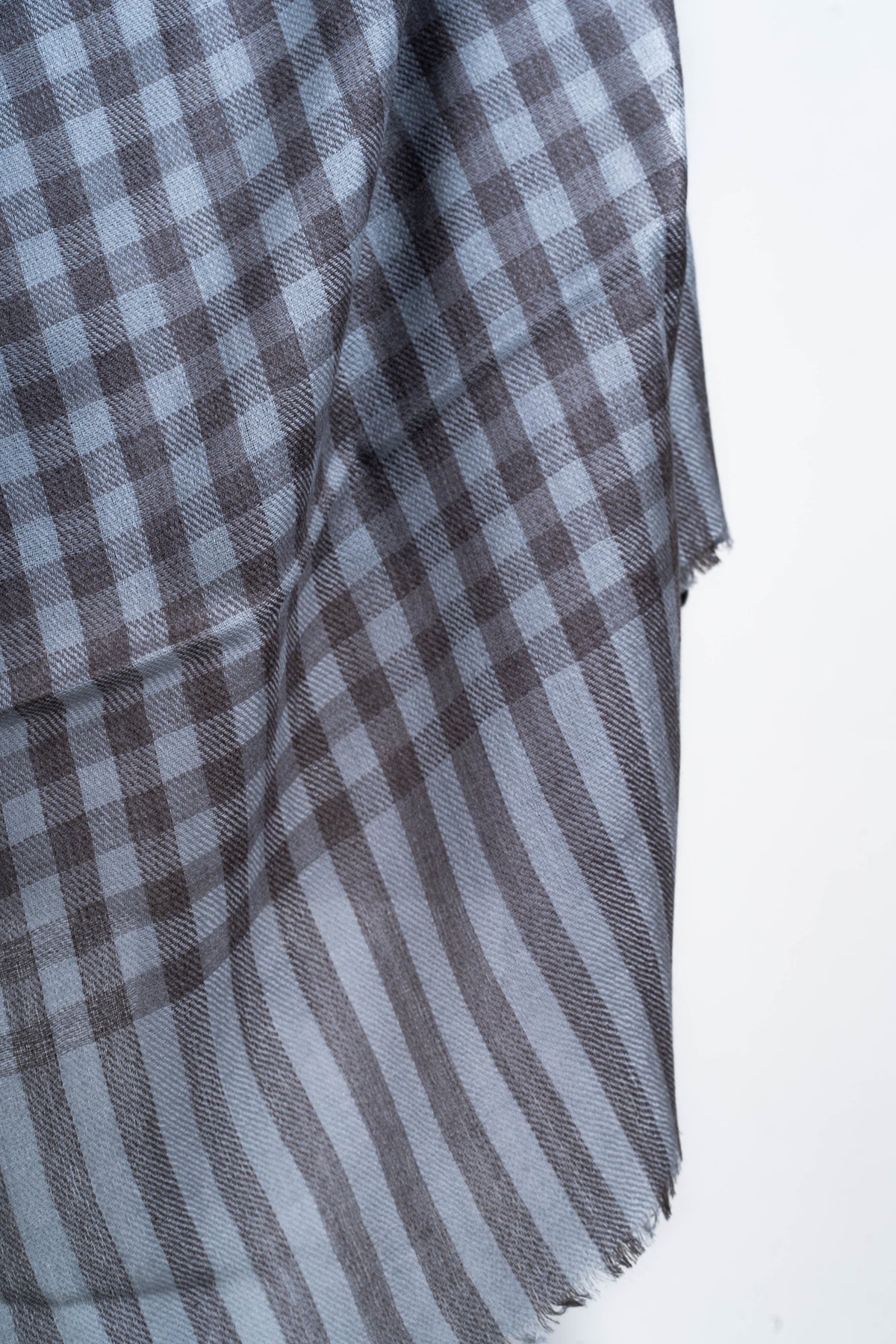 Detail of the grey stole end showing square checks transitioning to long stripes and a short fringed edge.