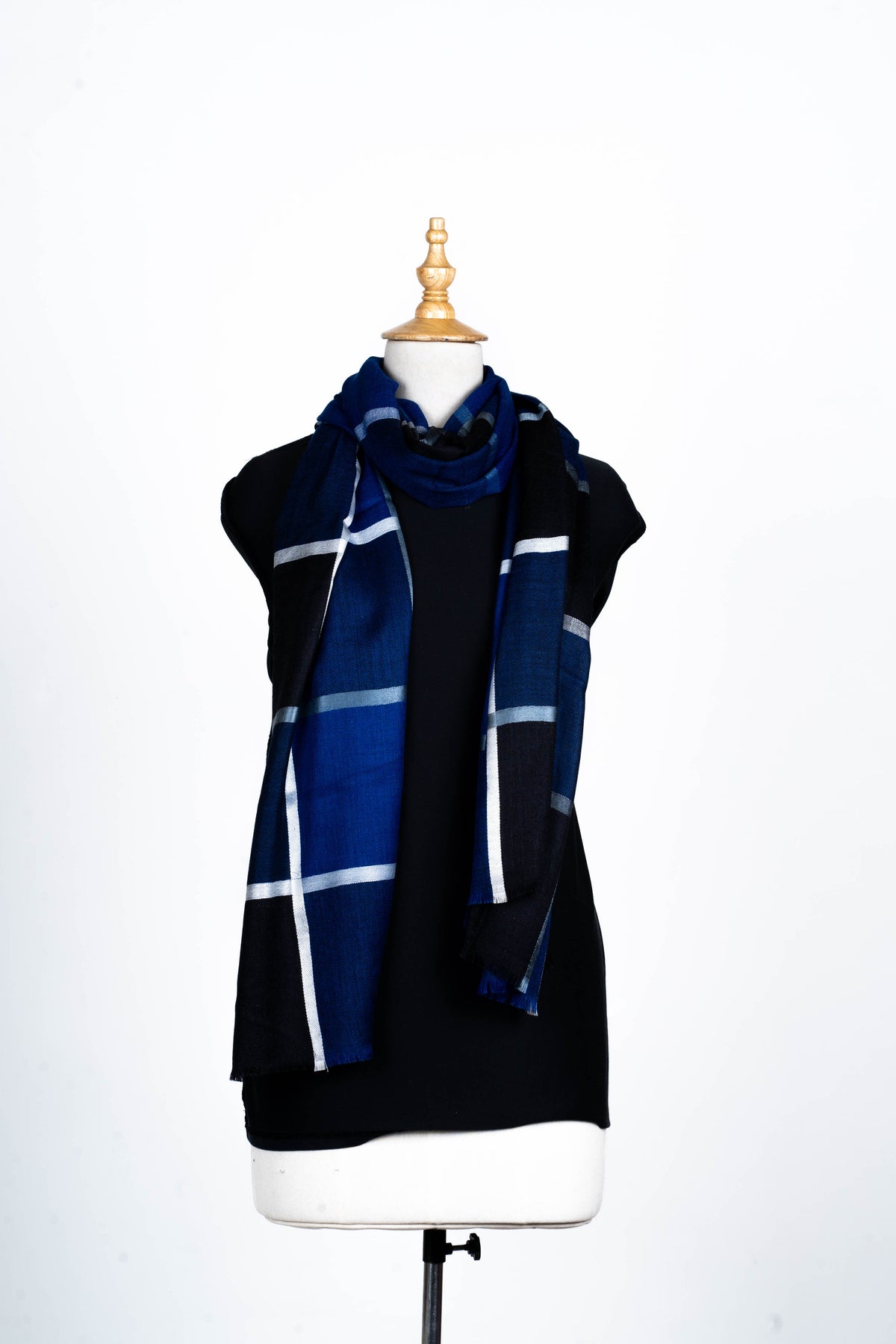 Full-length view of the navy and black checked stole looped over a black mannequin, with two long fringed ends