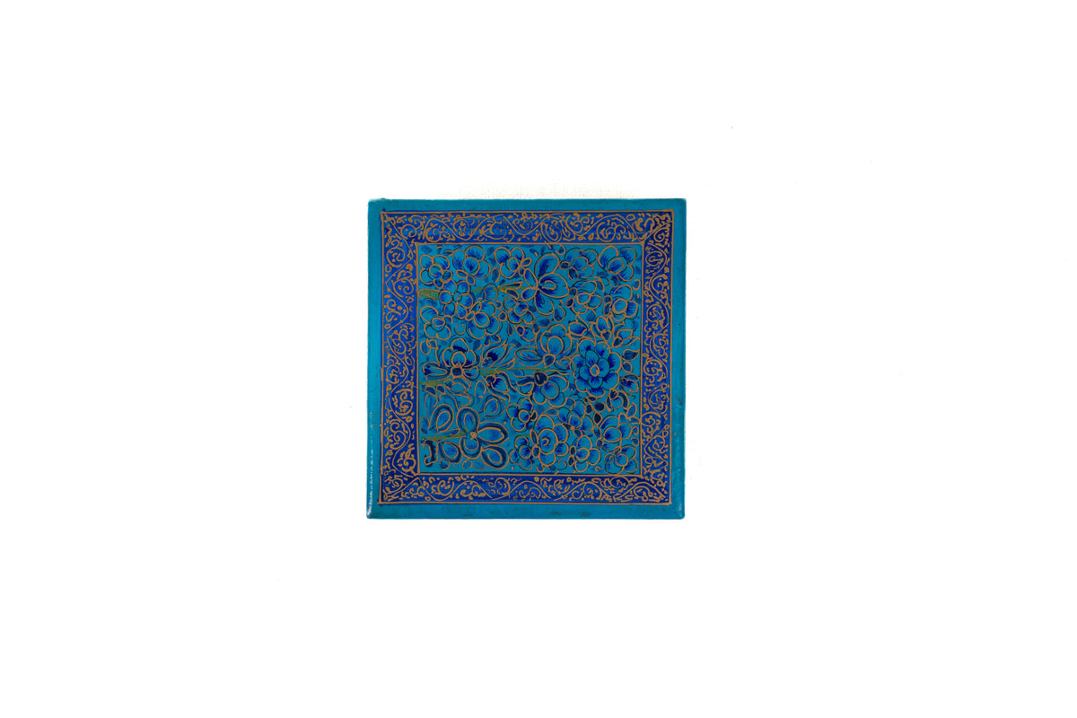 Top view of the square blue coaster box lid, painted with dense floral scrollwork and a narrow decorative border