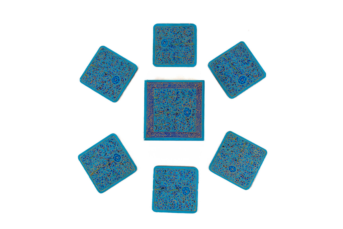 Six square blue floral coasters arranged in a circle around their matching decorative storage box
