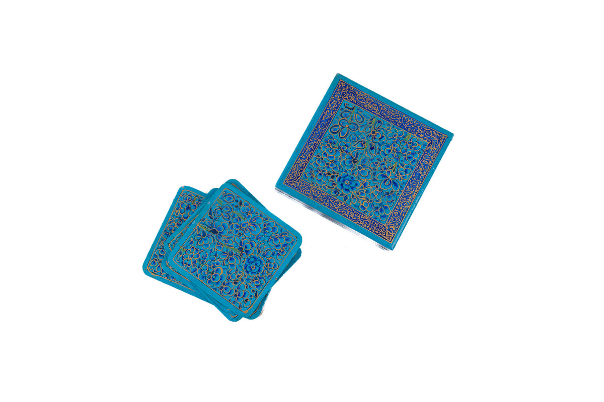 Overhead view of stacked blue floral papier-mâché coasters beside their matching square storage box