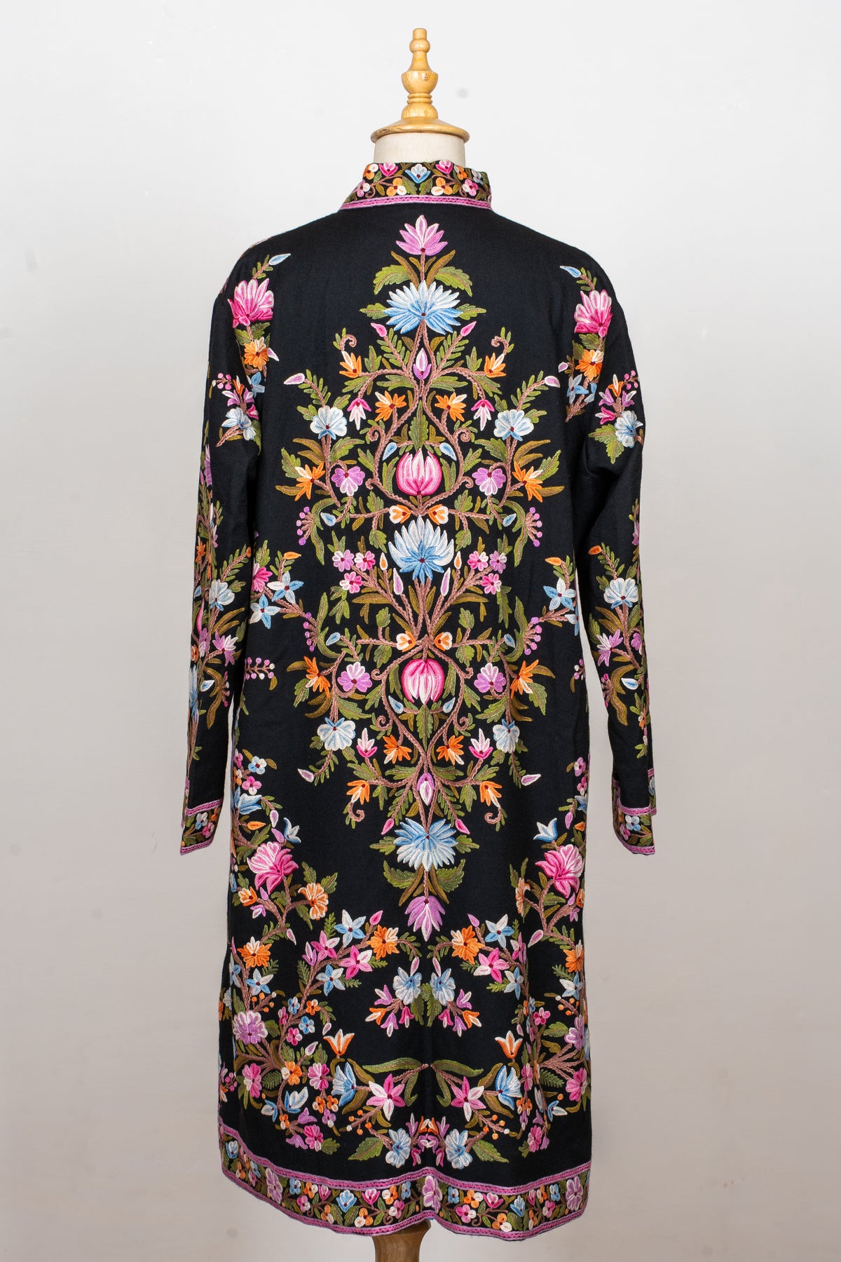 Full back view of the black jacket with a symmetrical column of pink and blue flowers, green vines and an embroidered hem