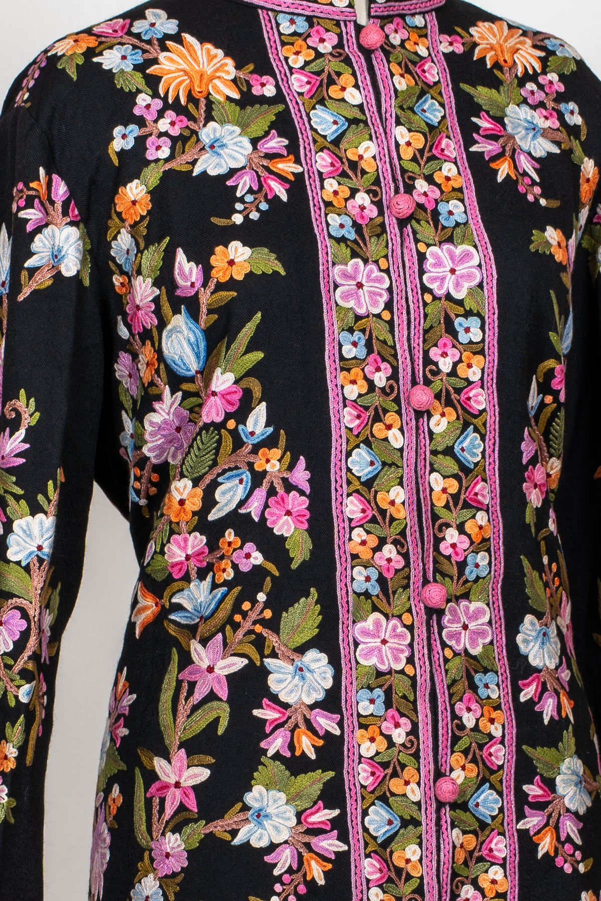 Detail of the black jacket’s floral front panels and sleeve, showing pink-blue flowers and narrow pink borders