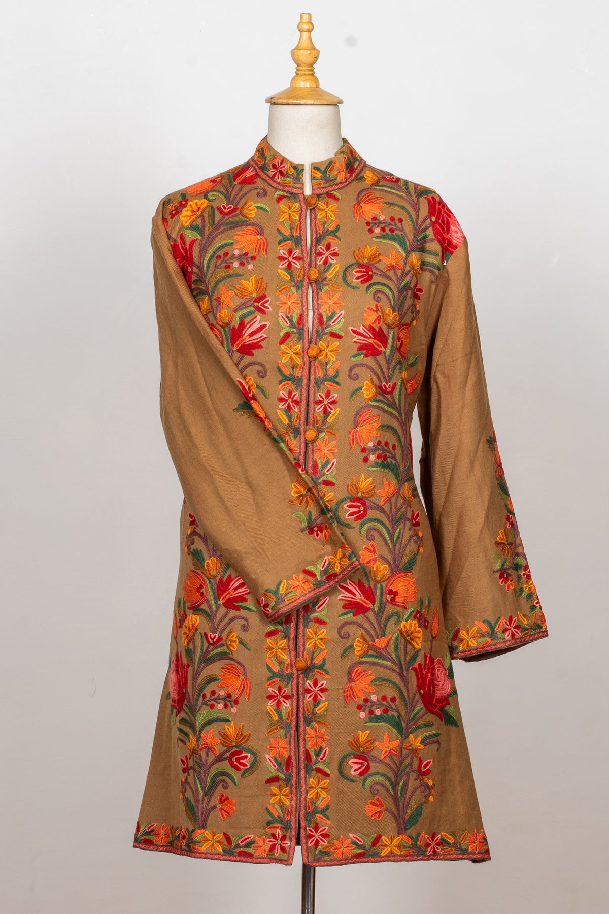 Front view of the earthy brown Hand Aari jacket with one sleeve crossed over its floral-embroidered front