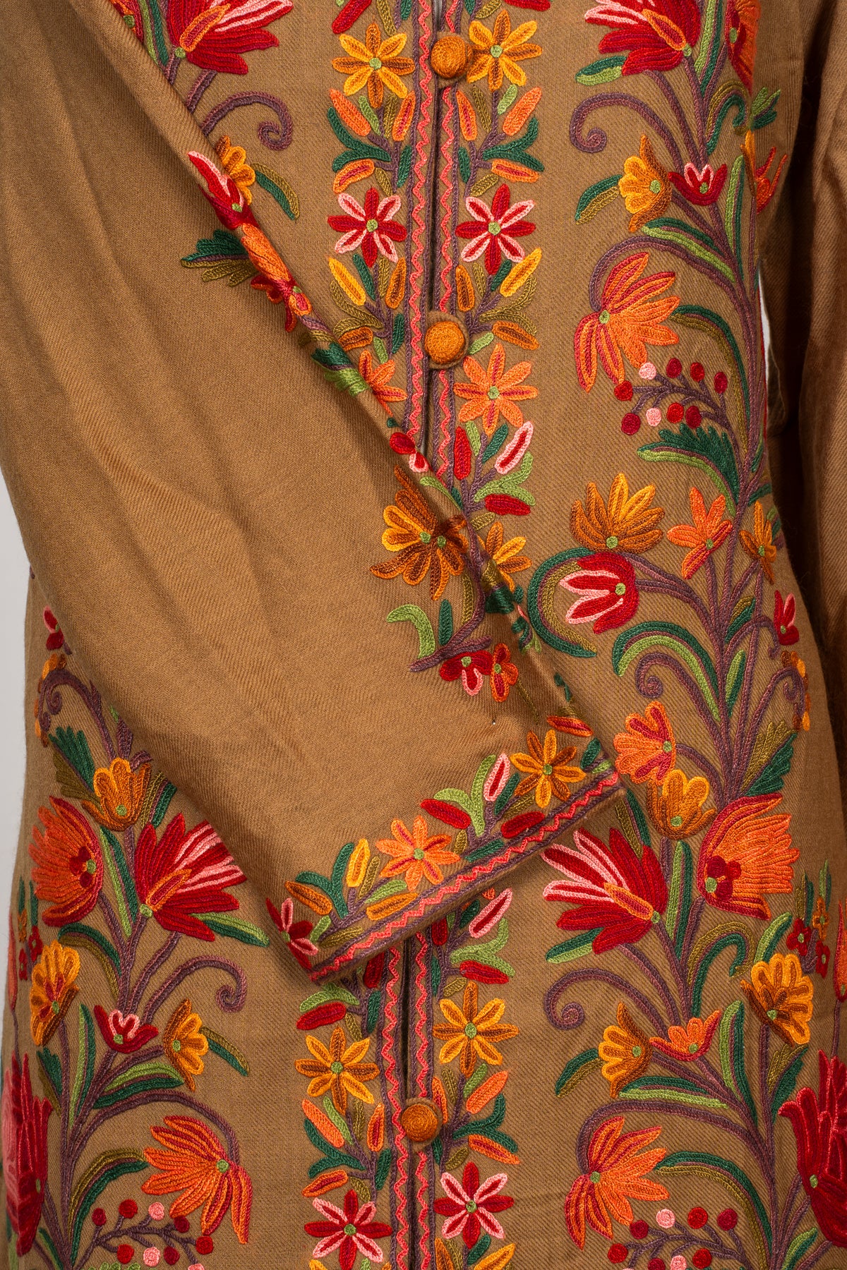 Crossed sleeve and cuff detail on the earthy brown Hand Aari jacket, against its colourful floral front panel