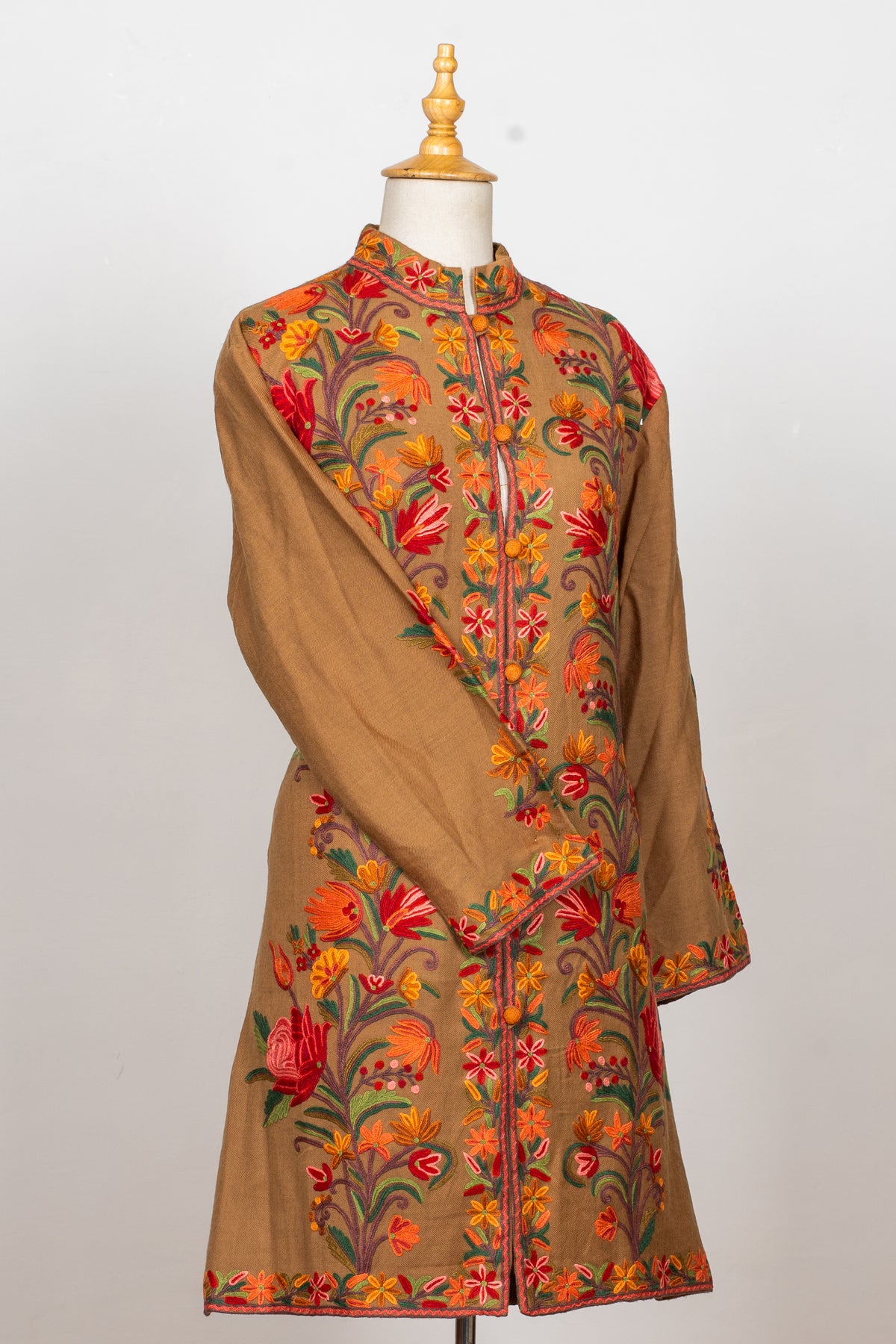 Angled front view of the earthy brown Hand Aari jacket, with one sleeve crossed over the body