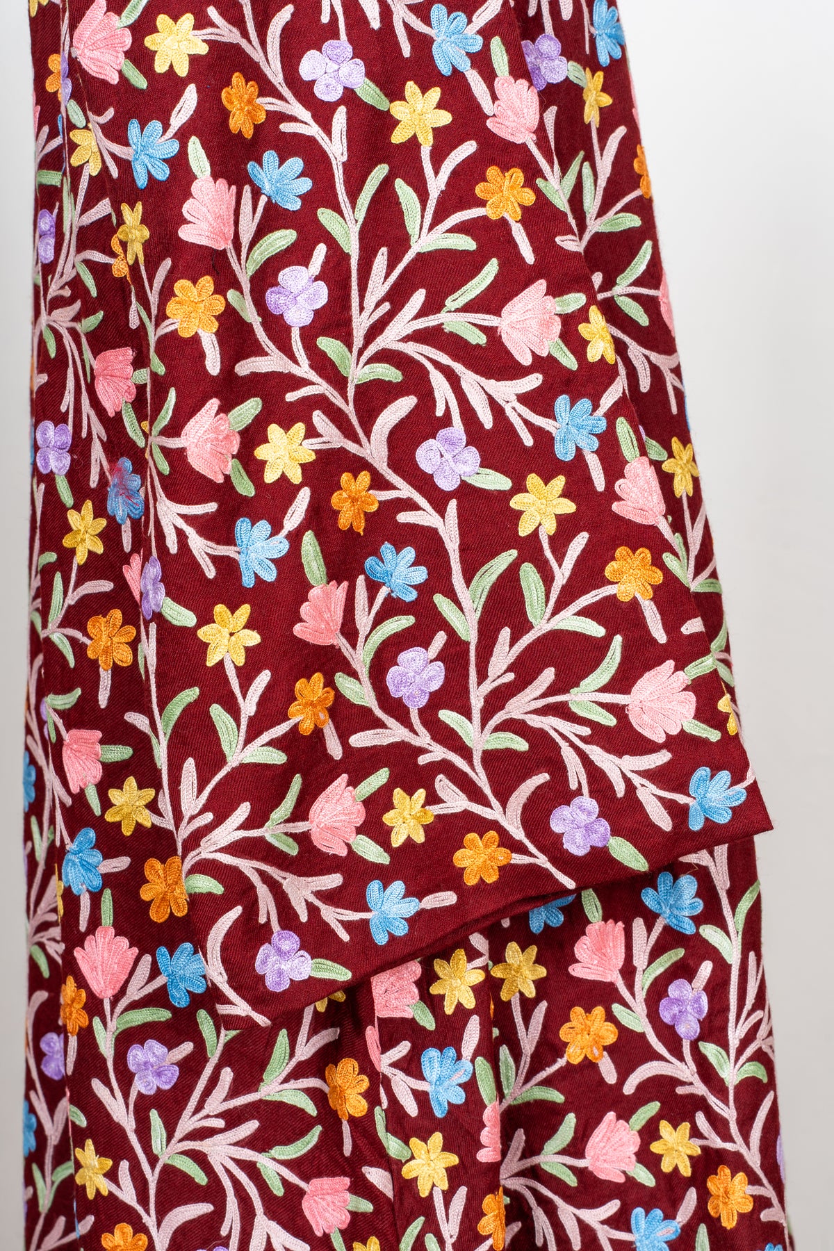 Detail of the abaya sleeve and cuff with dense floral embroidery continuing over the maroon body.