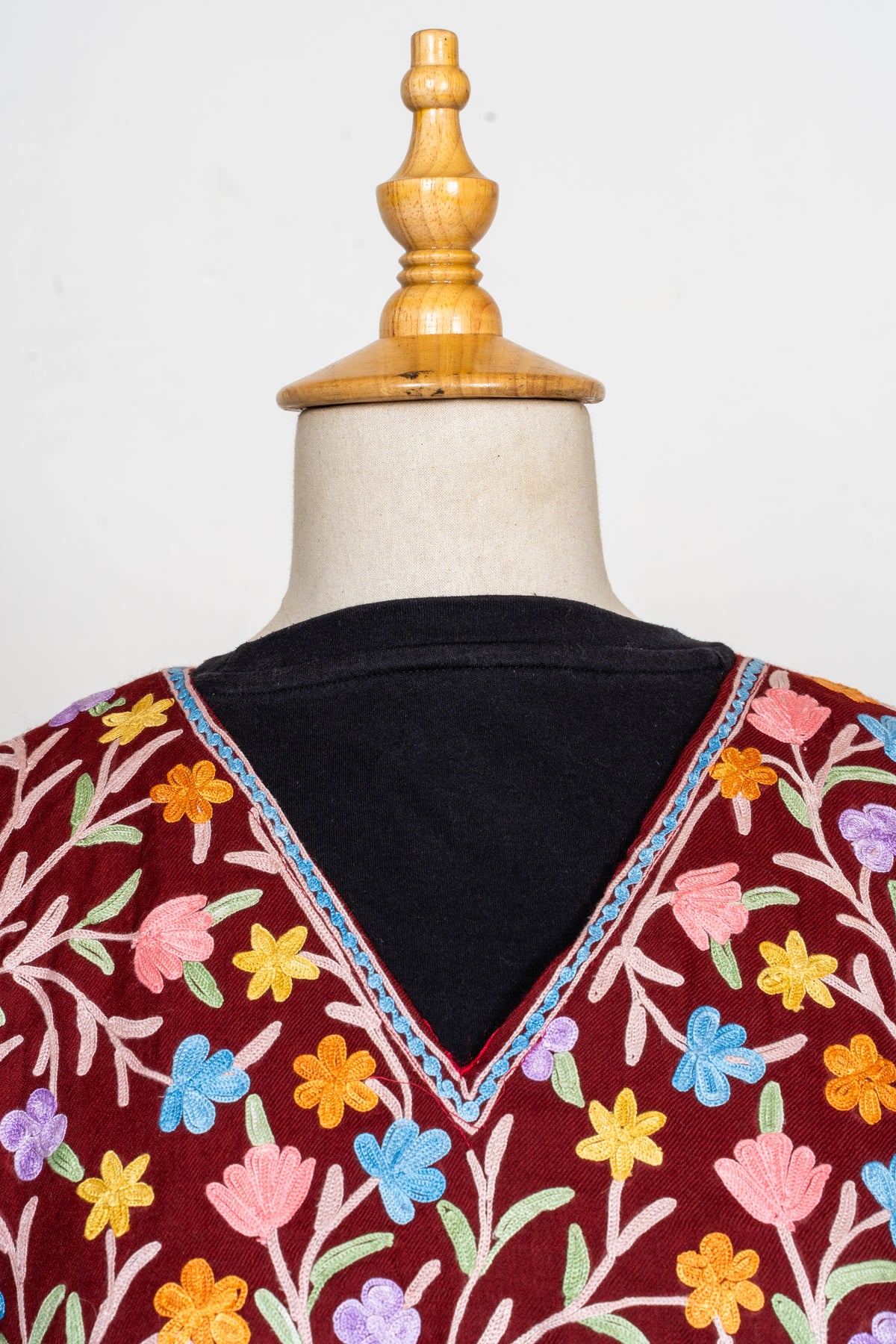 Close-up of the abaya V-neck with narrow blue edging among pink, blue, lilac and yellow embroidered flowers.