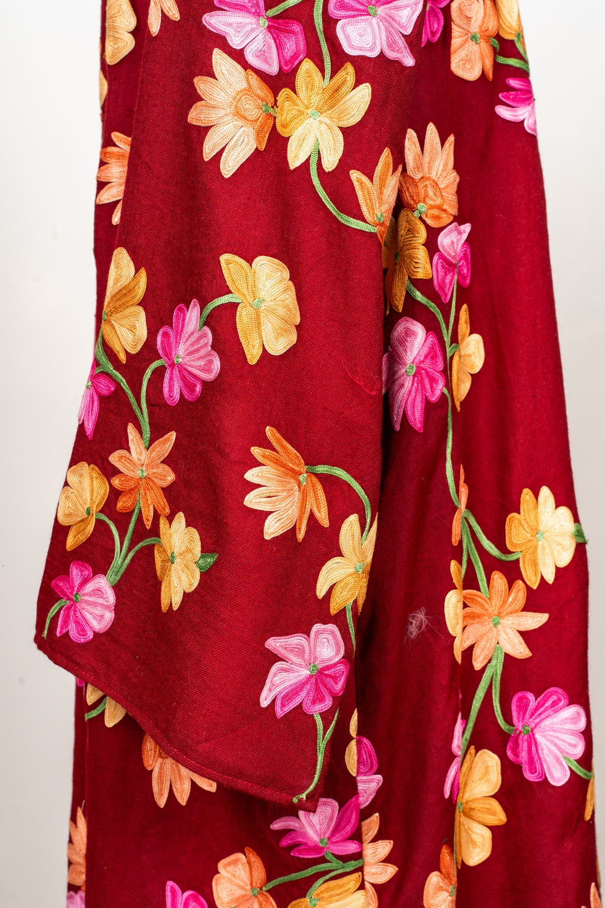 Detail of the crimson abaya’s sleeve, embroidered with pink and orange flowers on green stems