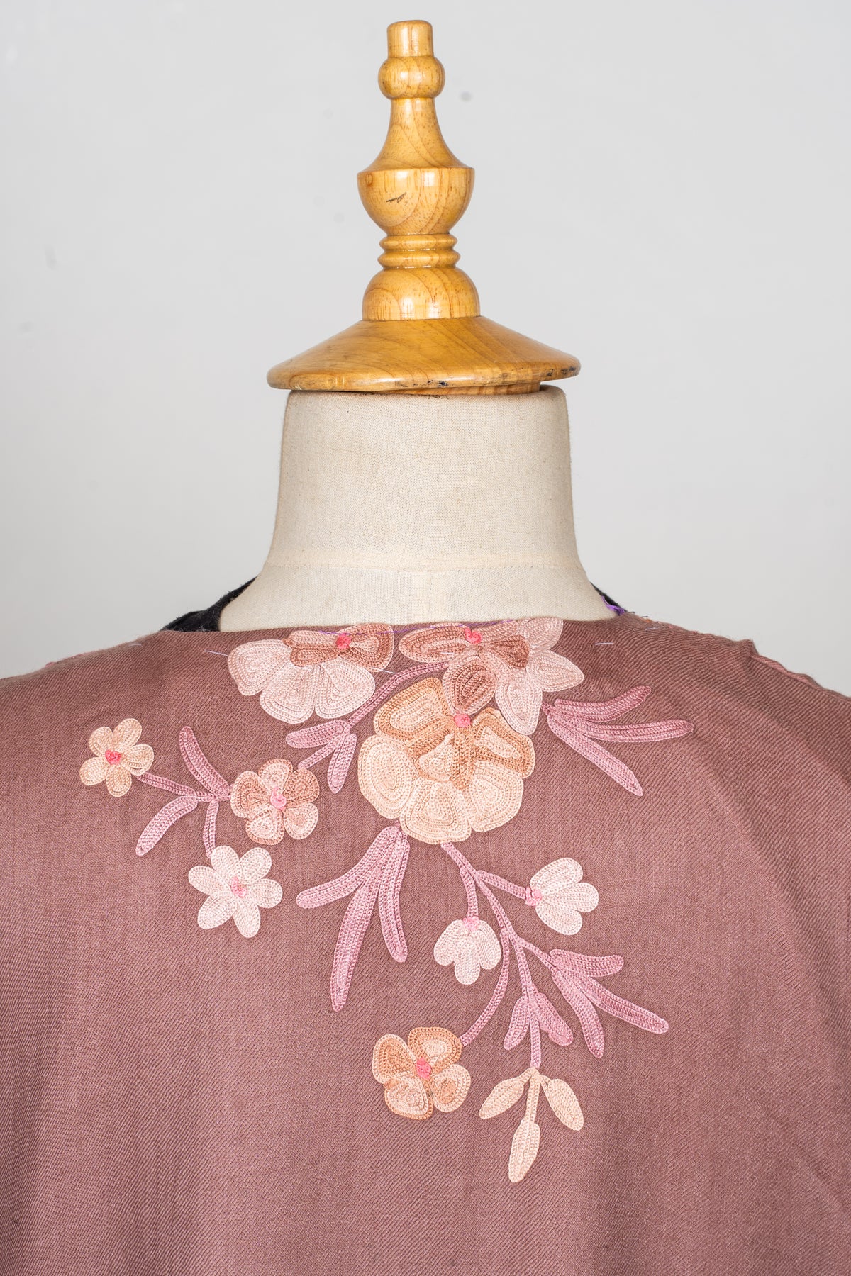 Upper-back detail of a dusty rose abaya with a pale Aari flower bouquet below the neckline
