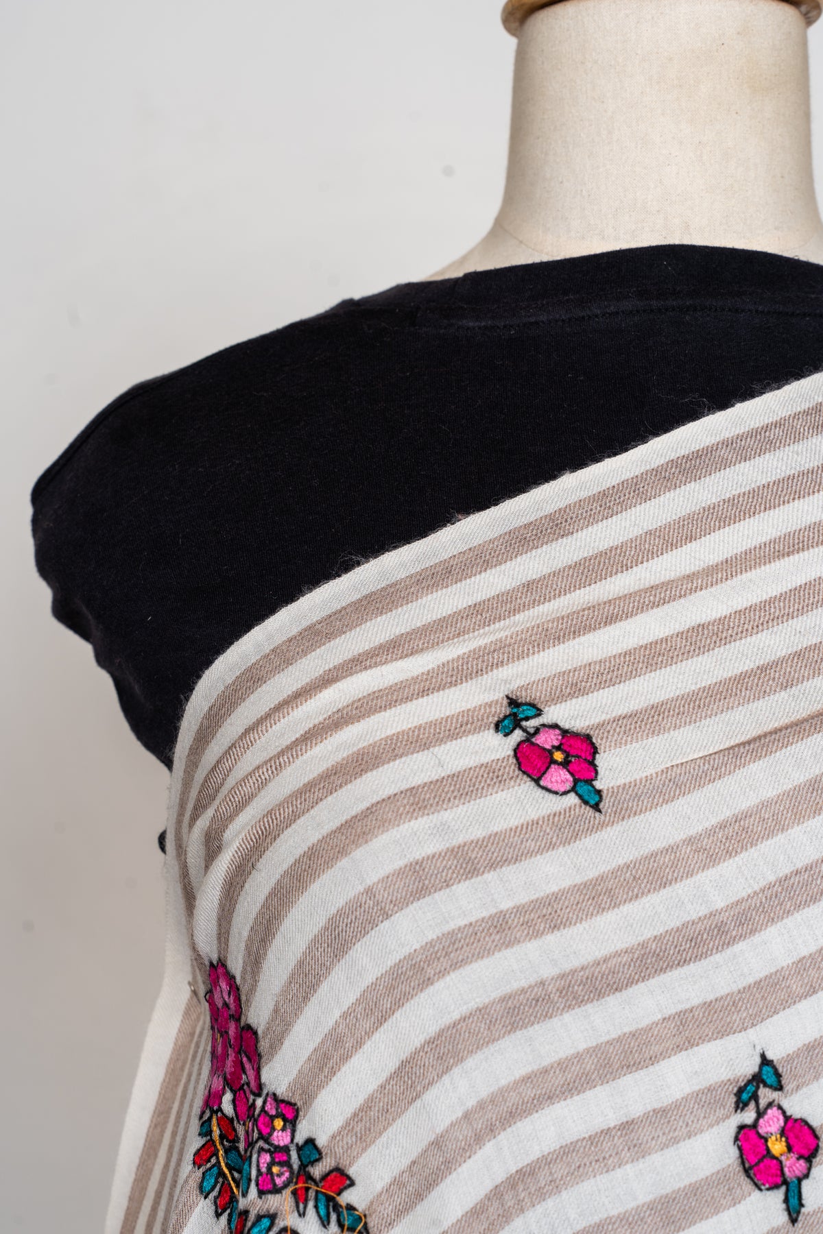 Close view of small fuchsia flowers with teal leaves on the shawl’s ivory and beige stripes
