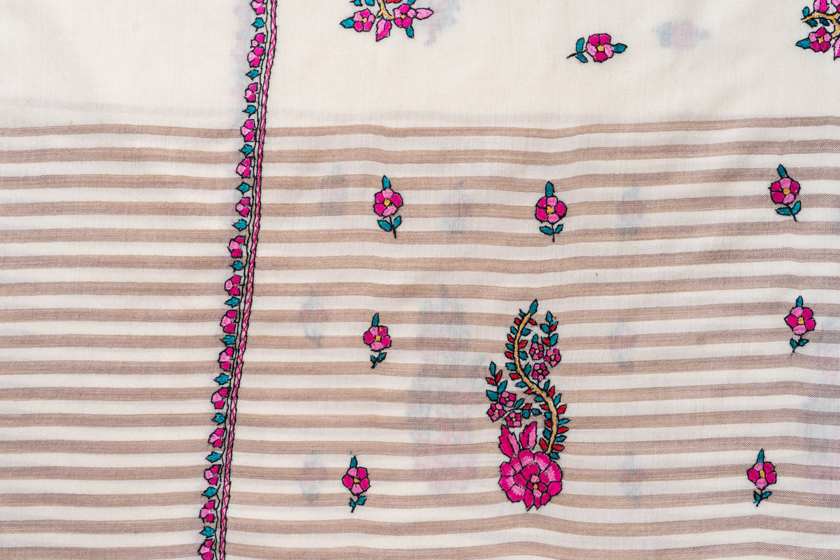 Beige striped section of the ivory shawl laid flat, with pink flowers, a large floral paisley and an embroidered edge