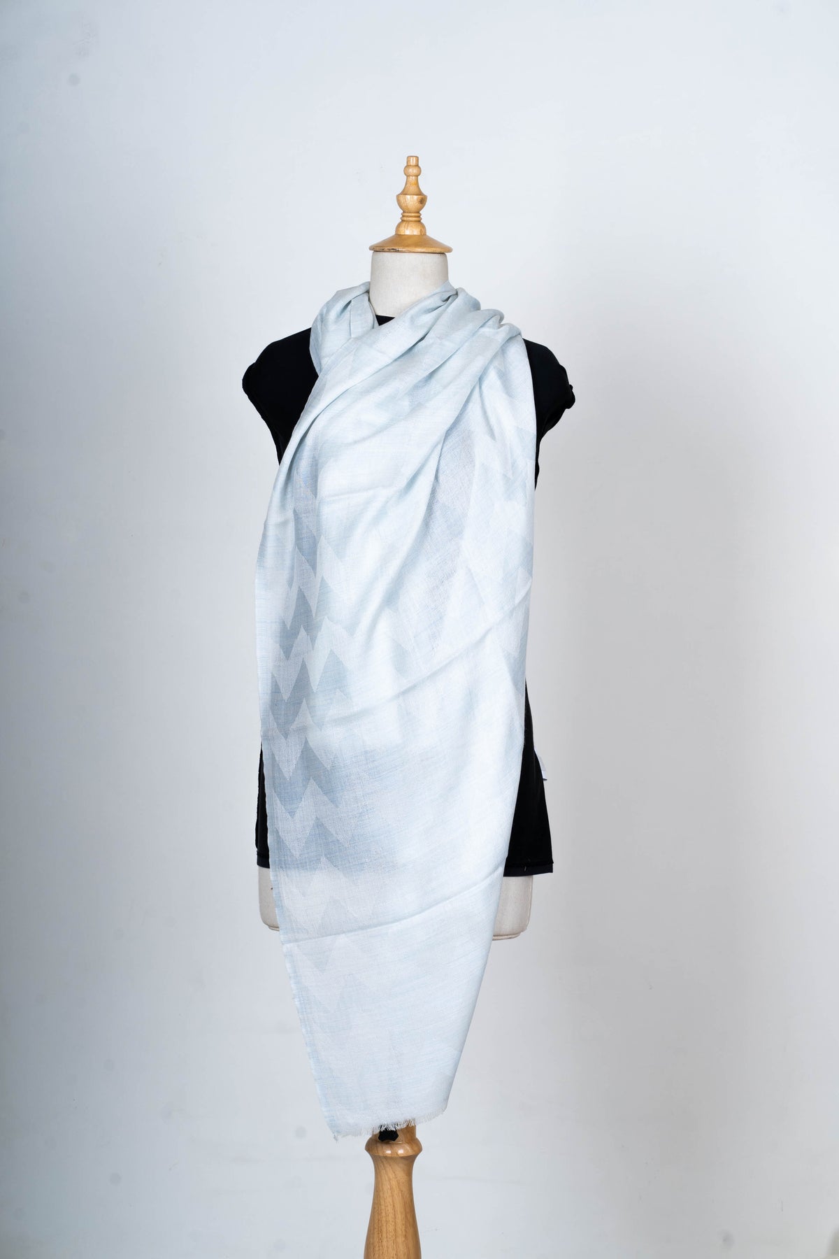 Full wrapped view of the pale blue stole on a mannequin, showing a long drape and subtle geometric pattern near the side.