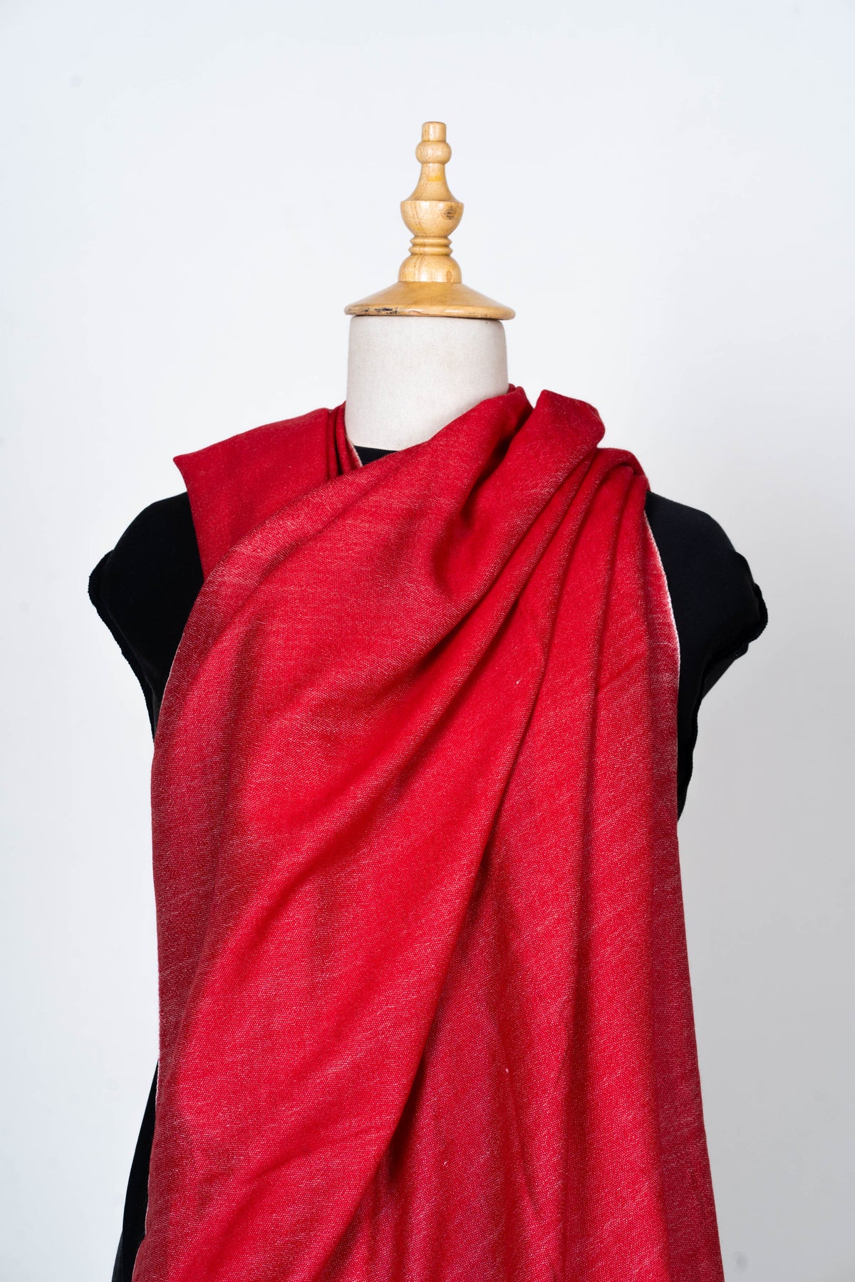 Scarlet stole wrapped across a mannequin chest and gathered over one shoulder, showing its subtle woven texture.