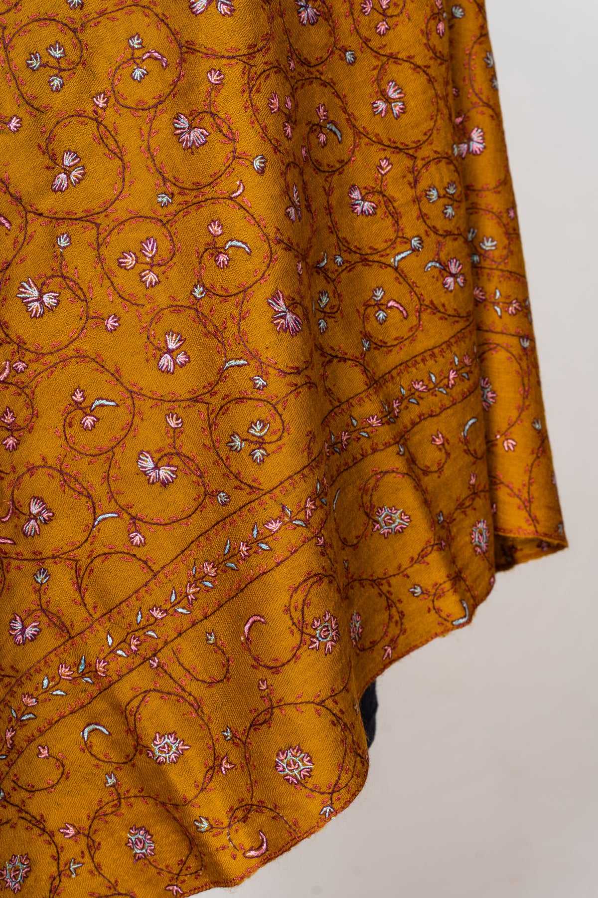 Hanging corner of a mustard stole with fine Sozni floral vines and a narrow pink and white border