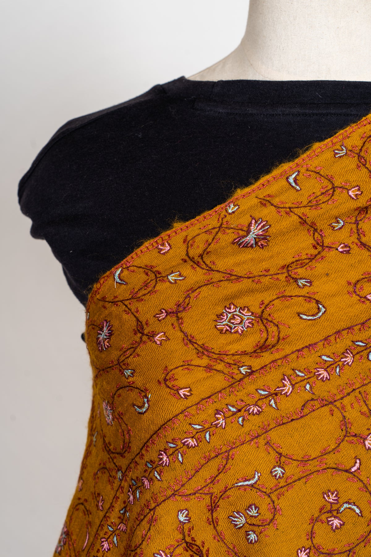 Shoulder detail of a mustard stole with small pink and white Sozni flowers on curling maroon vines