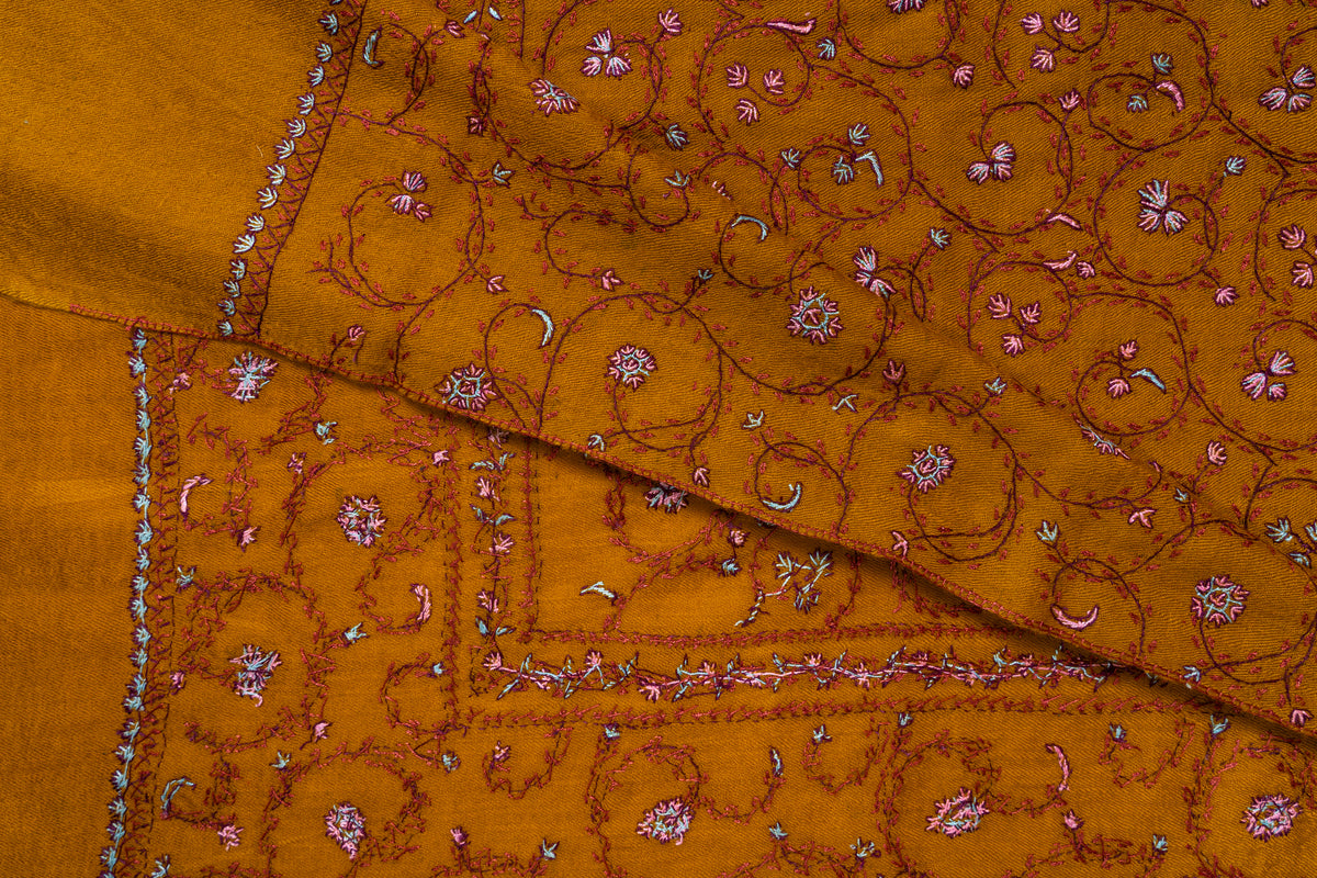Overlapping mustard stole corners showing pink and white Sozni floral stitching and narrow borders