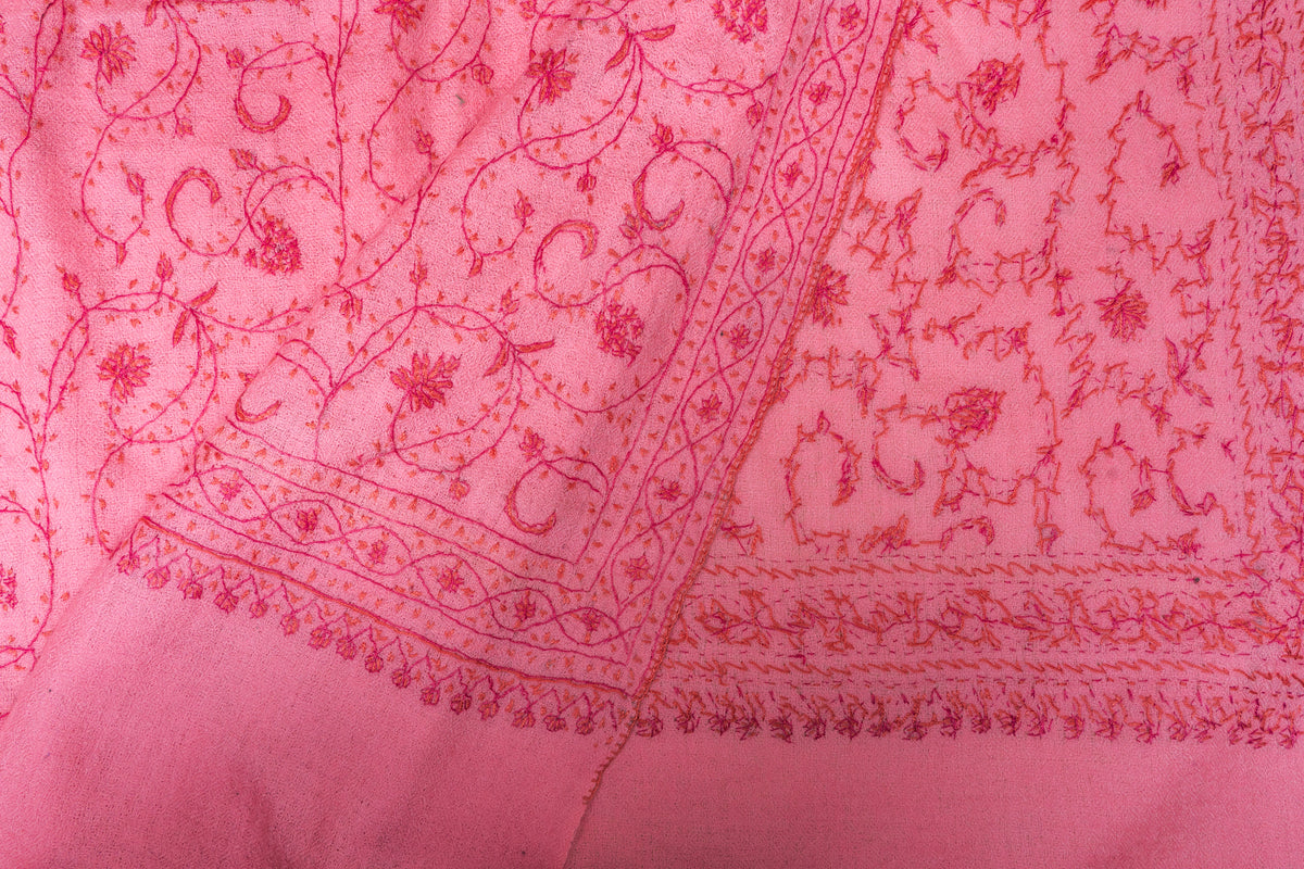 Folded corner of the pink Sozni stole showing its floral border and exposed reverse stitching