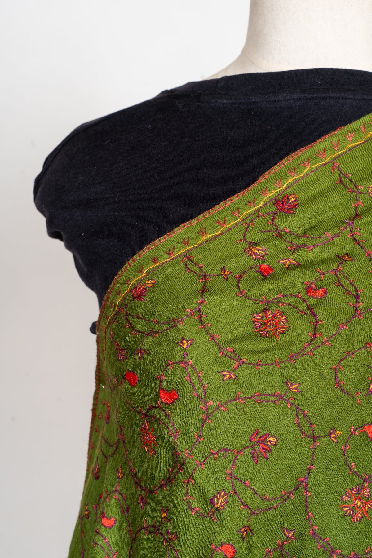 Detail of an olive-green stole's narrow gold-toned shoulder edging and delicate Sozni floral vines