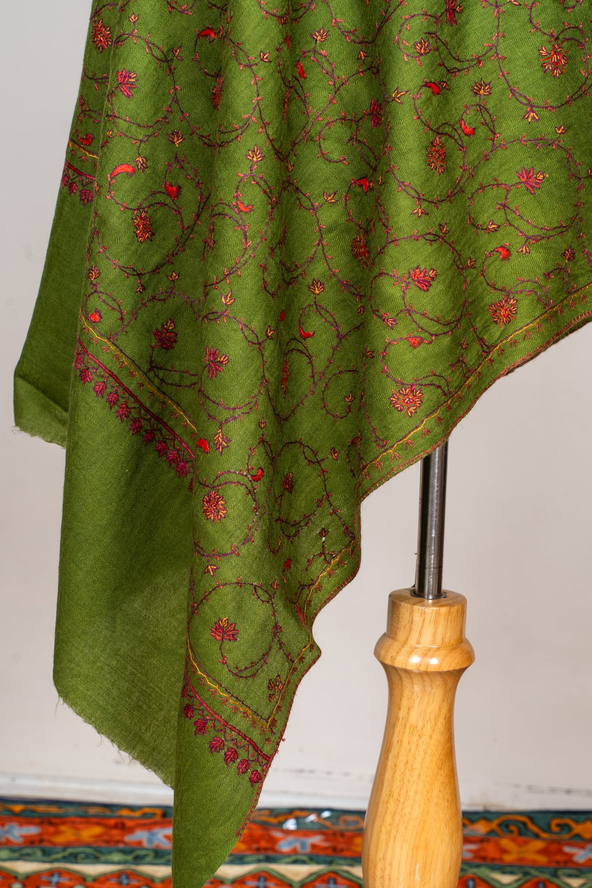 Hanging end of an olive-green stole, showing floral Sozni vines, a narrow gold-toned border and a plain green margin