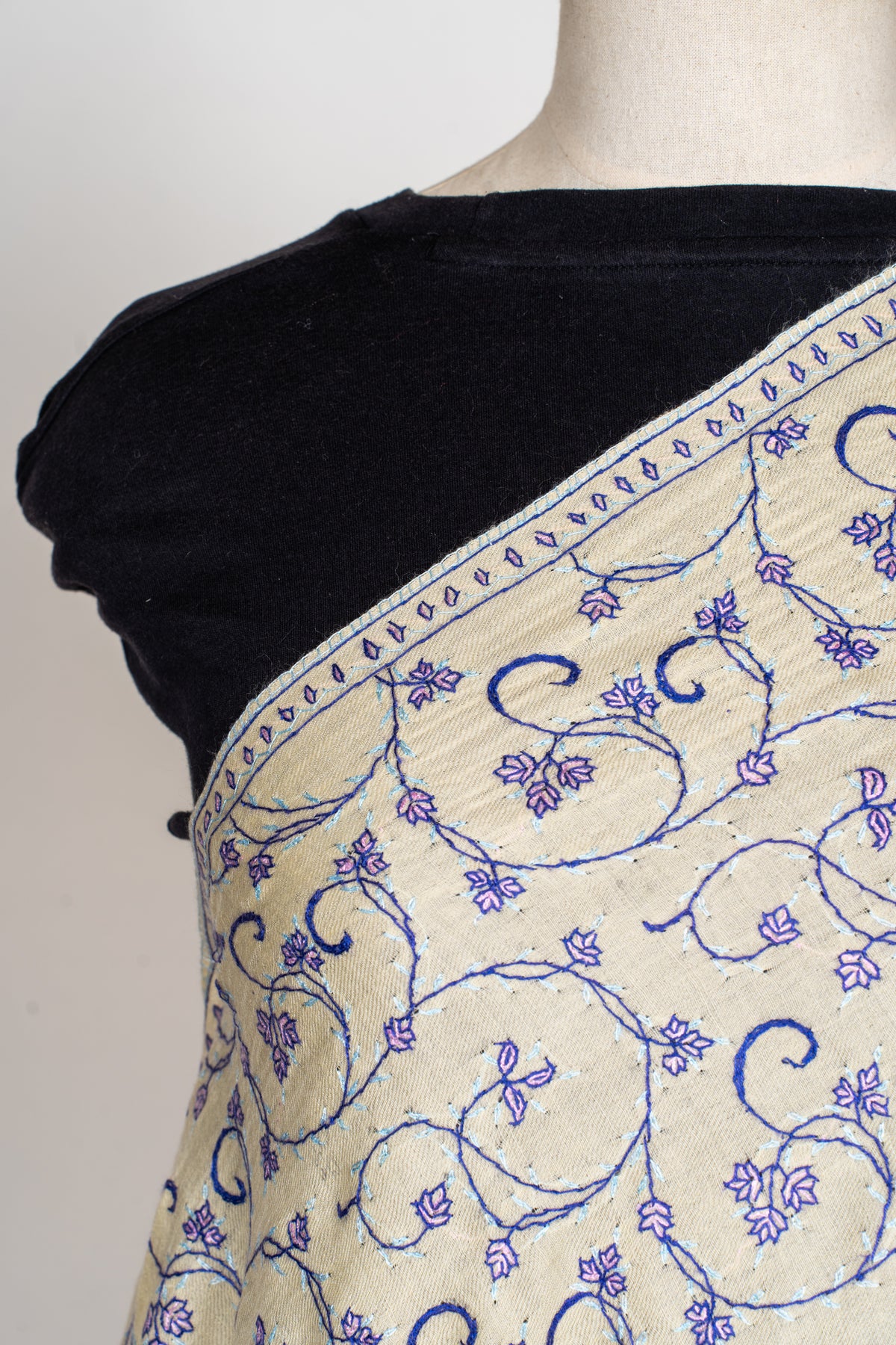 Close-up of a cream stole across a mannequin's chest, showing purple floral vines and a narrow leaf-patterned edge