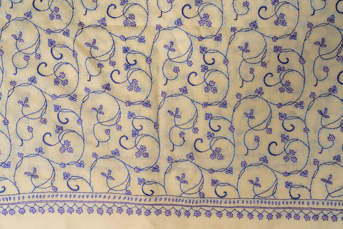 Close-up of curling purple floral embroidery and the narrow leaf-and-flower border on a cream stole