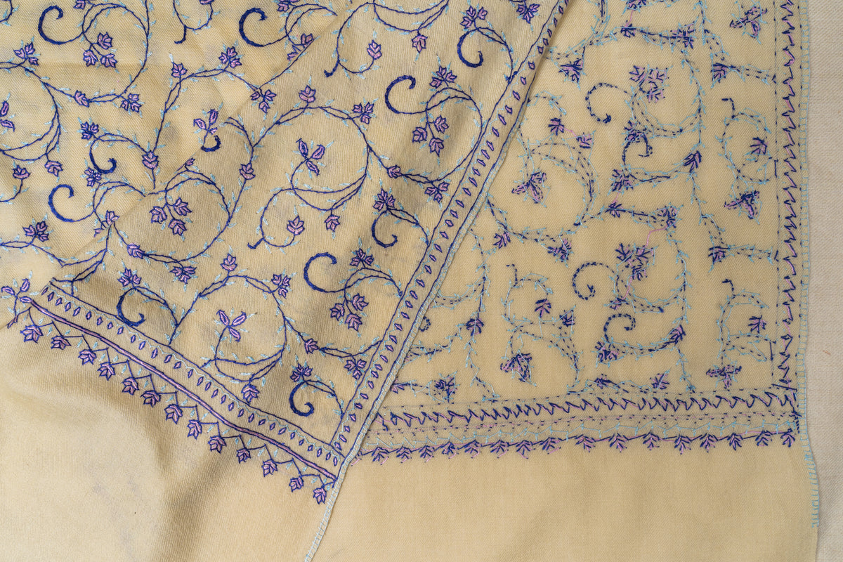 Folded corner of a cream stole showing the front and reverse of purple floral embroidery and its patterned border