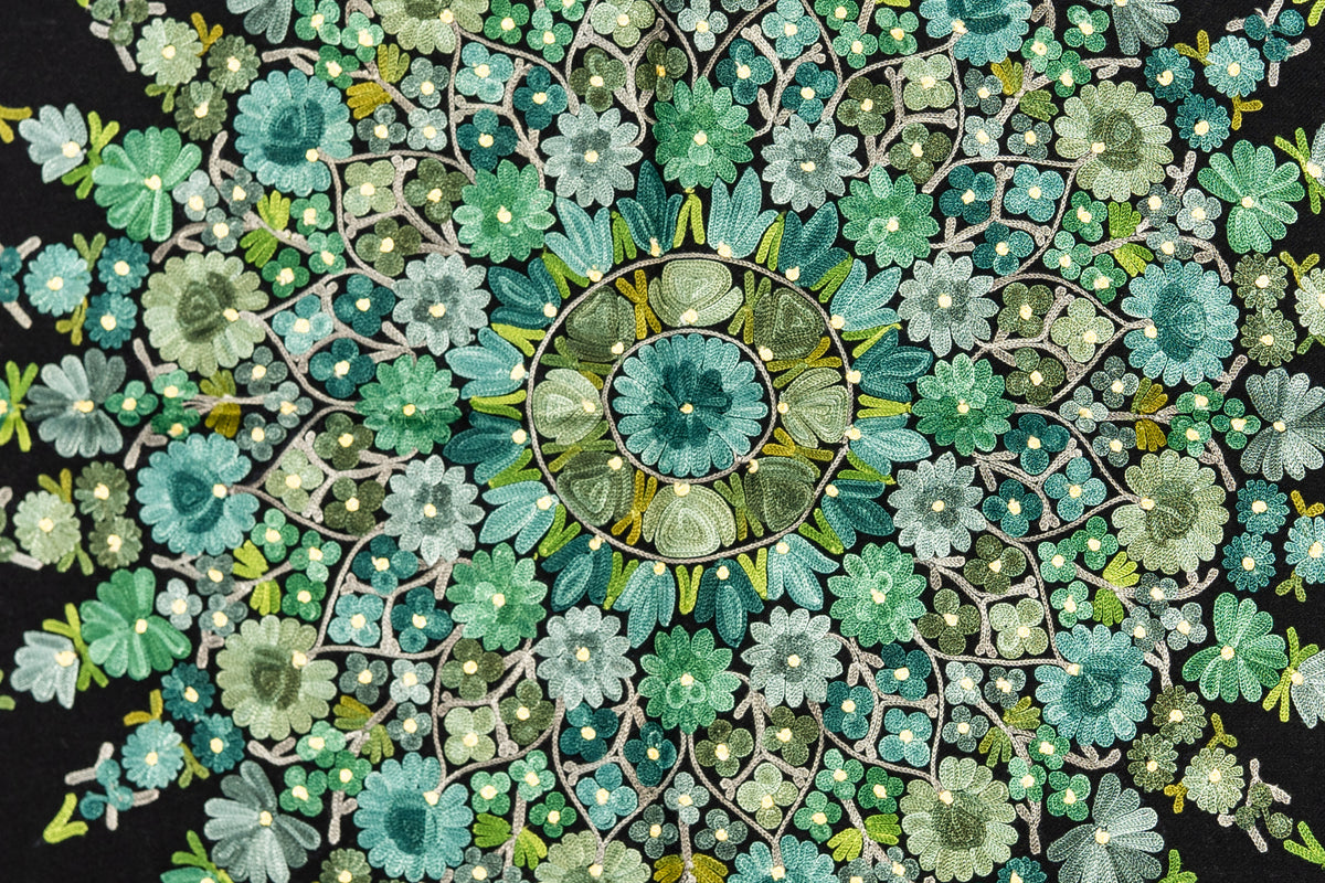 Close-up of the stole’s circular Aari medallion, with concentric flowers and fine branching stems in shades of green and mint.