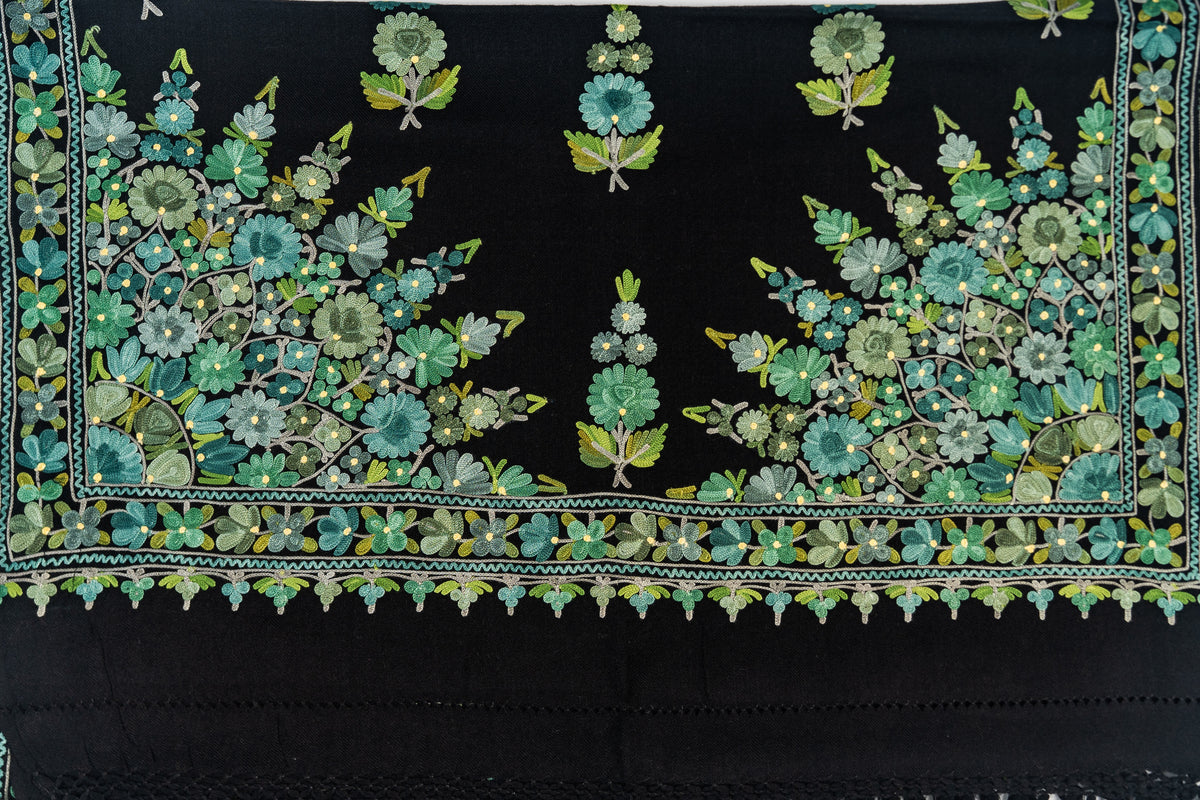 Flat detail of the black stole’s end with dense green floral corners, scattered sprigs and a narrow floral border.