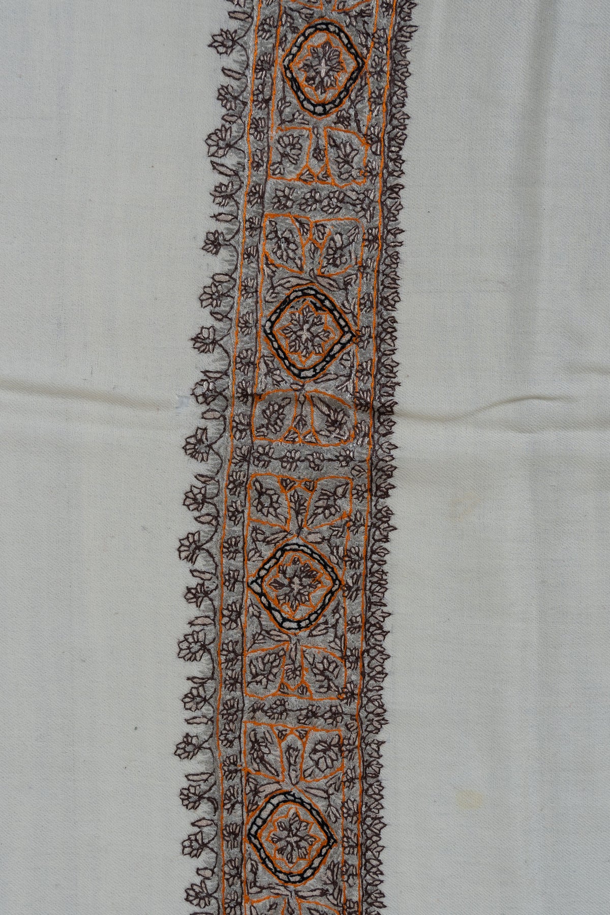 Close-up of an ivory rumal border with charcoal floral latticework, repeating medallions and ochre outlines