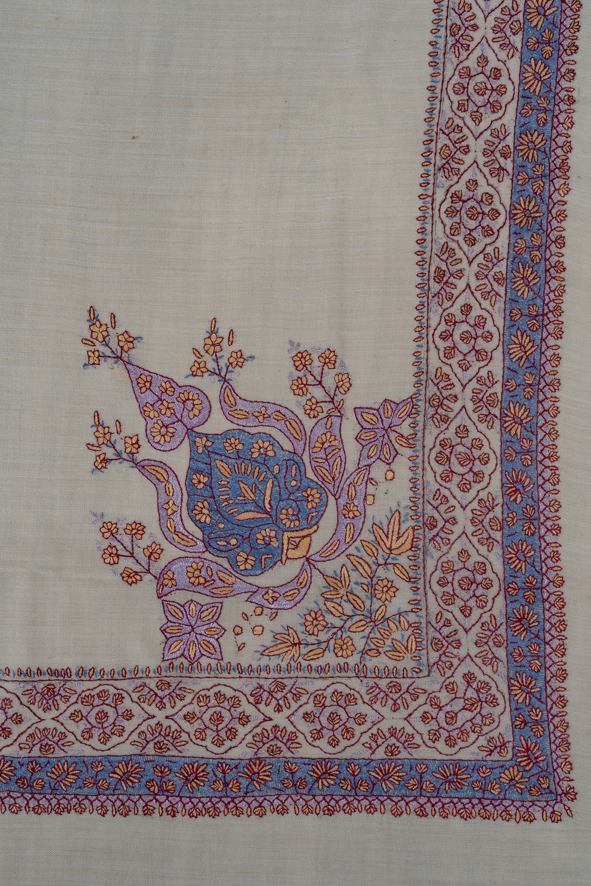 Pearl-coloured rumal corner with blue and lavender paisley and floral embroidery framed by a two-band floral border