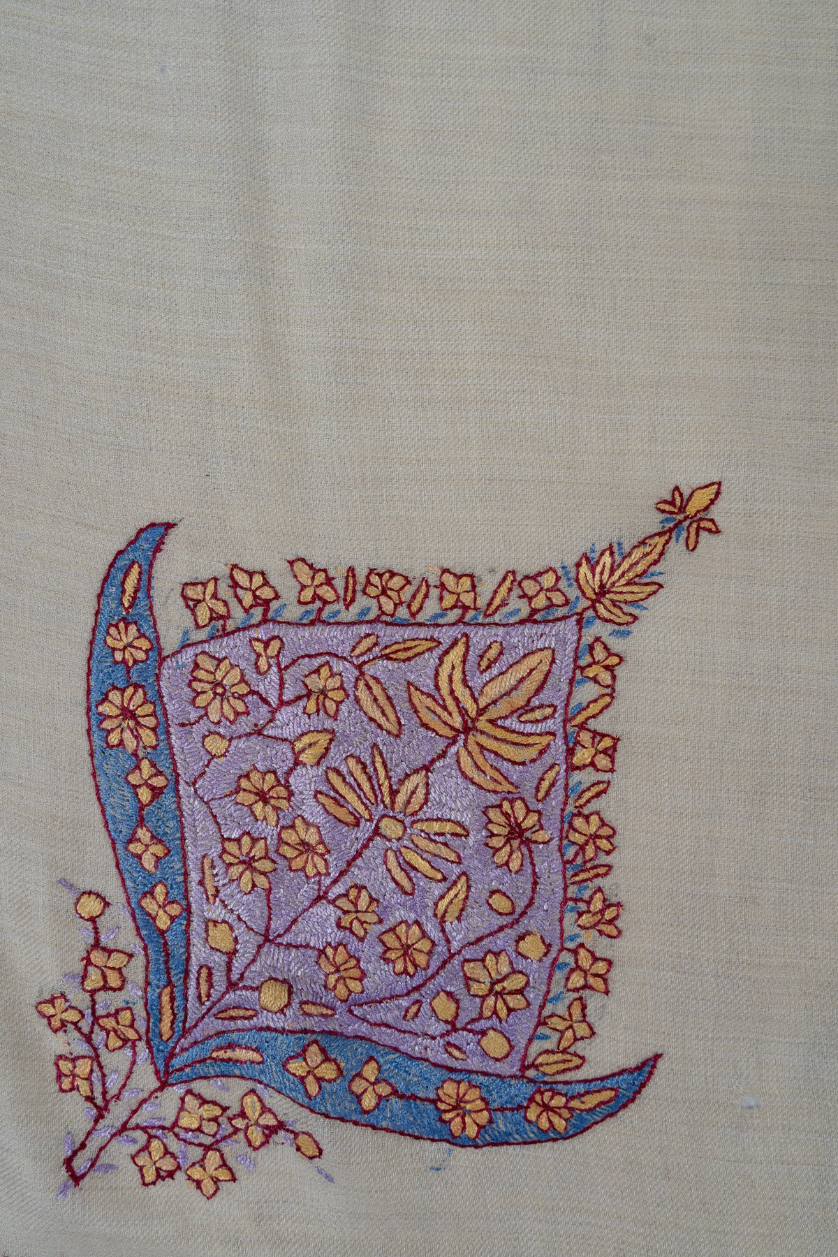 Lavender leaf-shaped Sozni motif filled with coral-outlined flowers and framed by blue curved leaves on a pearl rumal