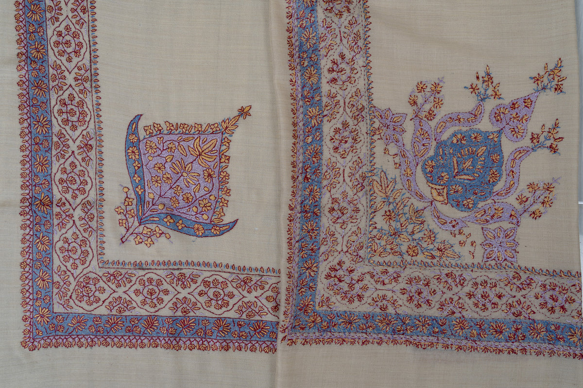 Overlapping corners of a pearl rumal, showing both sides of blue, lavender and coral Sozni embroidery