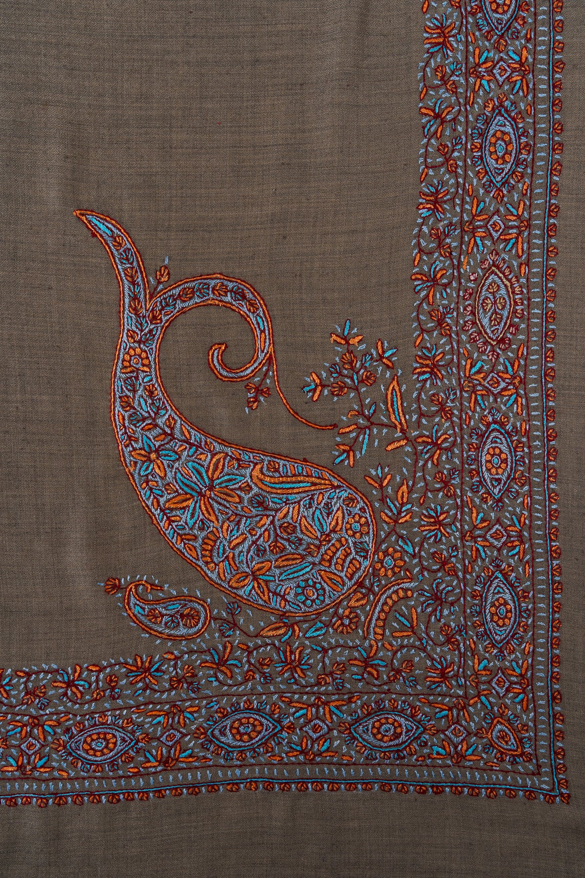 Cedar-brown rumal corner with a large curling paisley filled with turquoise and copper flowers beside a matching border
