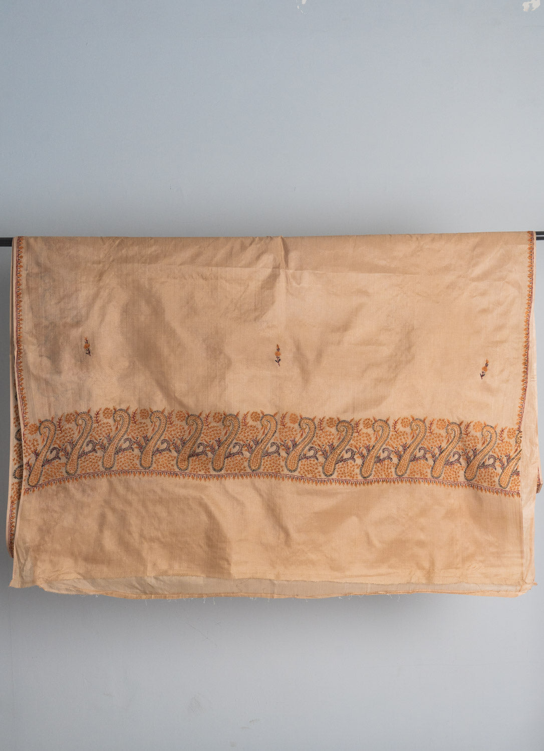 Ivory tabby silk saree end spread across a grey background, with a Sozni paisley band between broad plain sections.