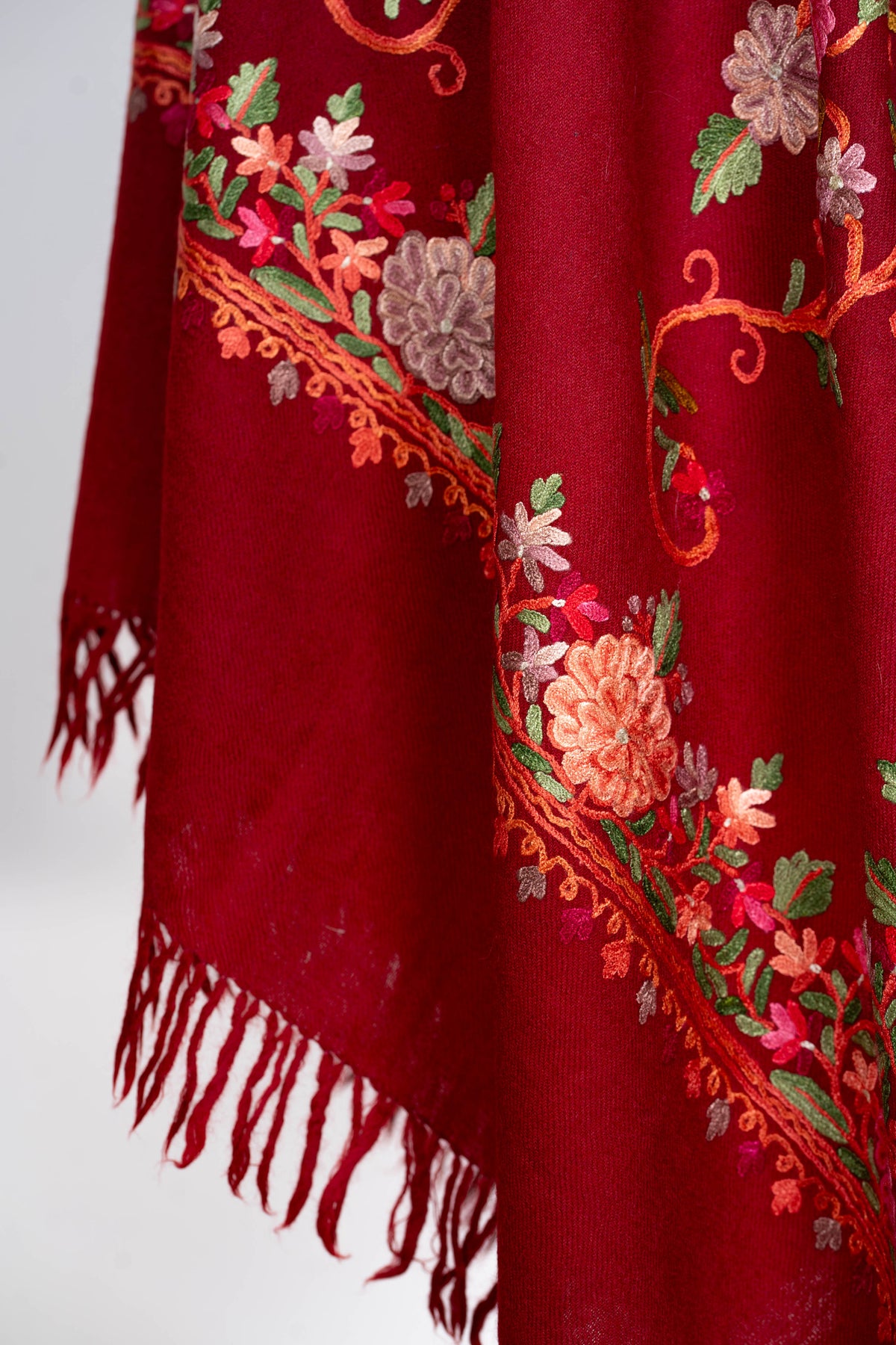 Hanging crimson stole corner with a pink and coral Aari floral border above red fringe